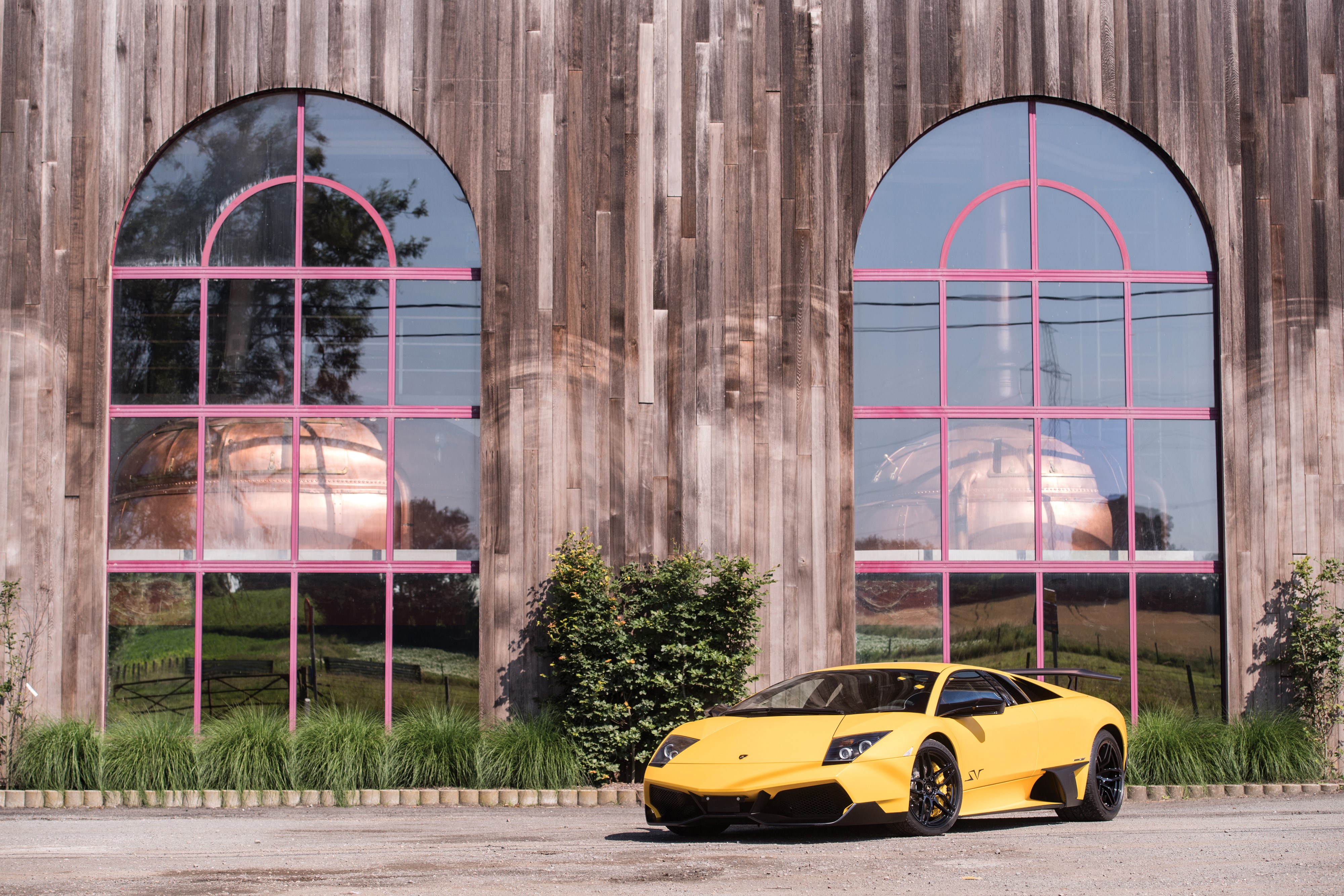 Yellow Lamborghini in front of a wooden building with arched windows HD Wallpaper