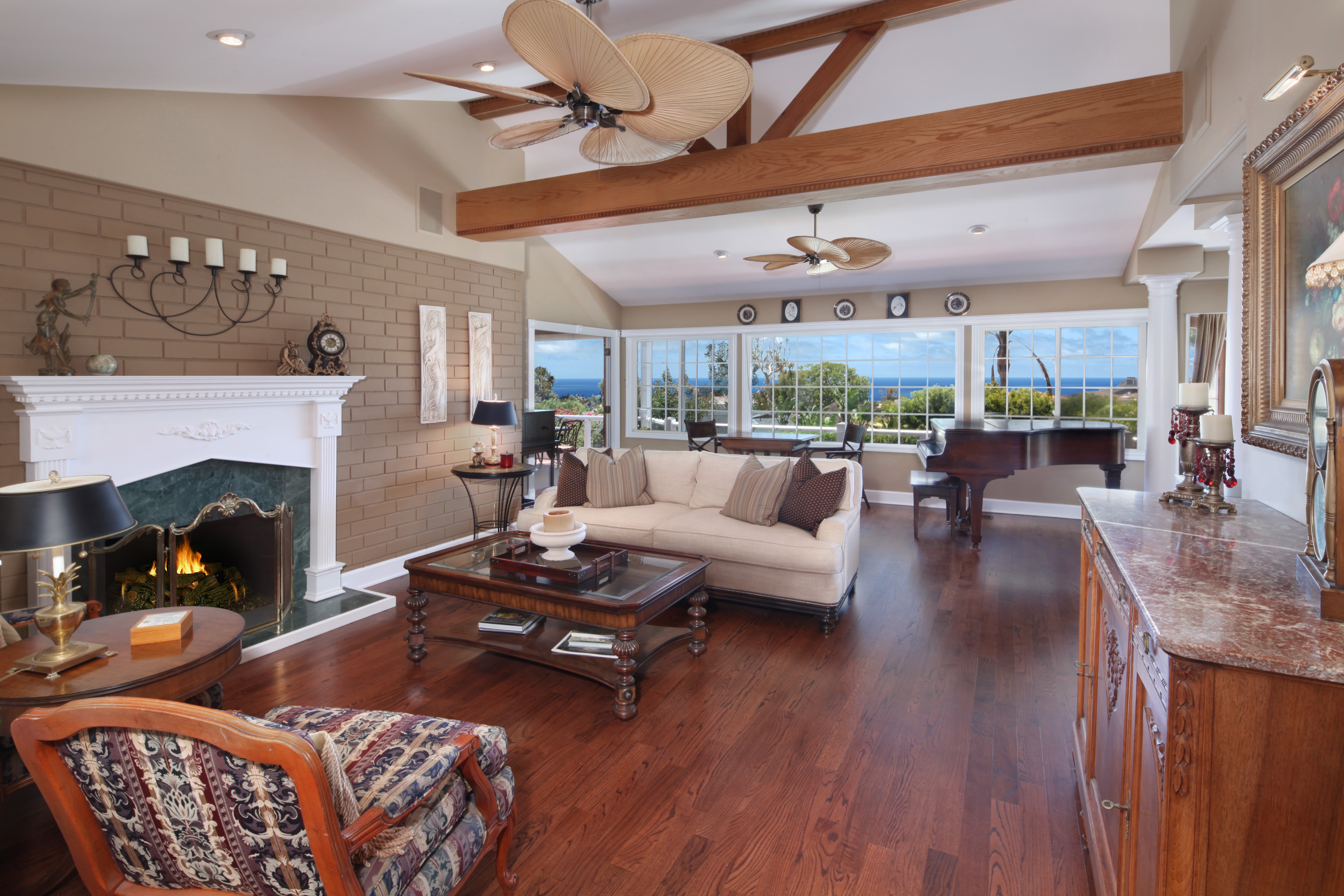 Living room with fireplace, sofa, armchair, and ocean view HD Wallpaper