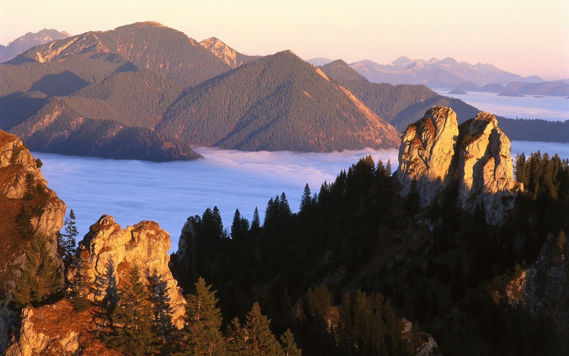 Mountain peaks above a sea of clouds at sunrise HD Wallpaper