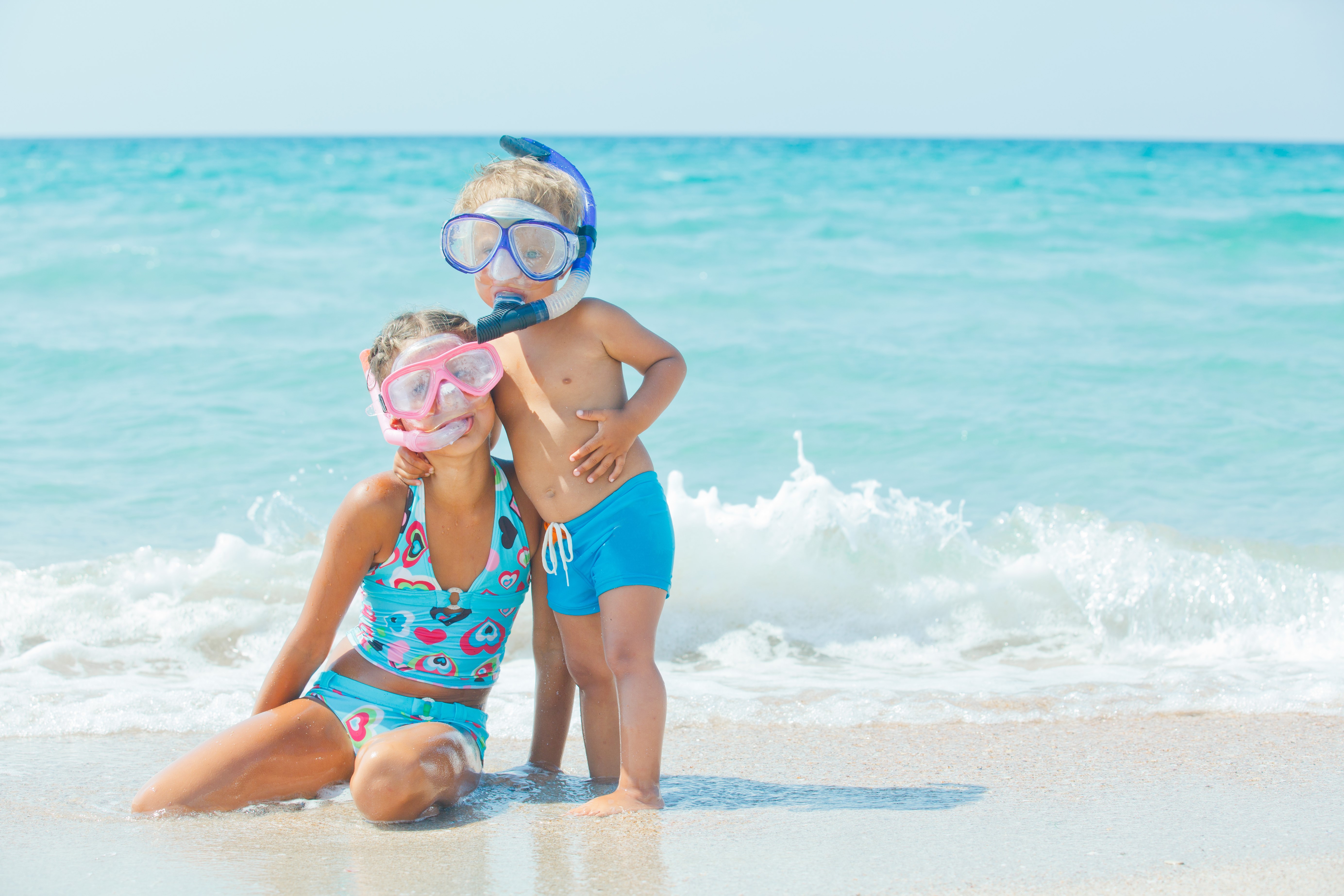 Two children with snorkeling gear on a beach HD Wallpaper