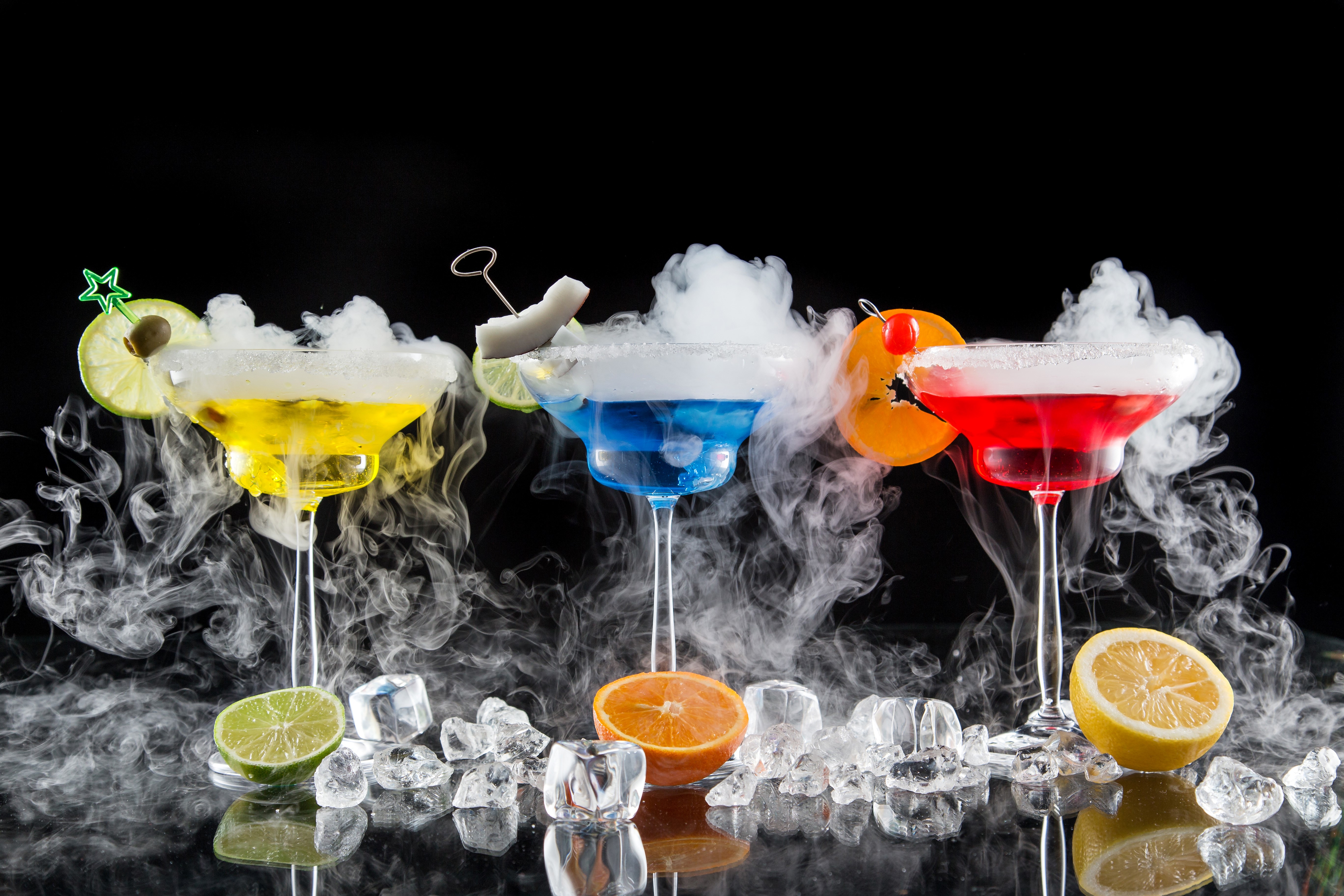 Three colorful cocktails with smoke and citrus garnishes HD Wallpaper