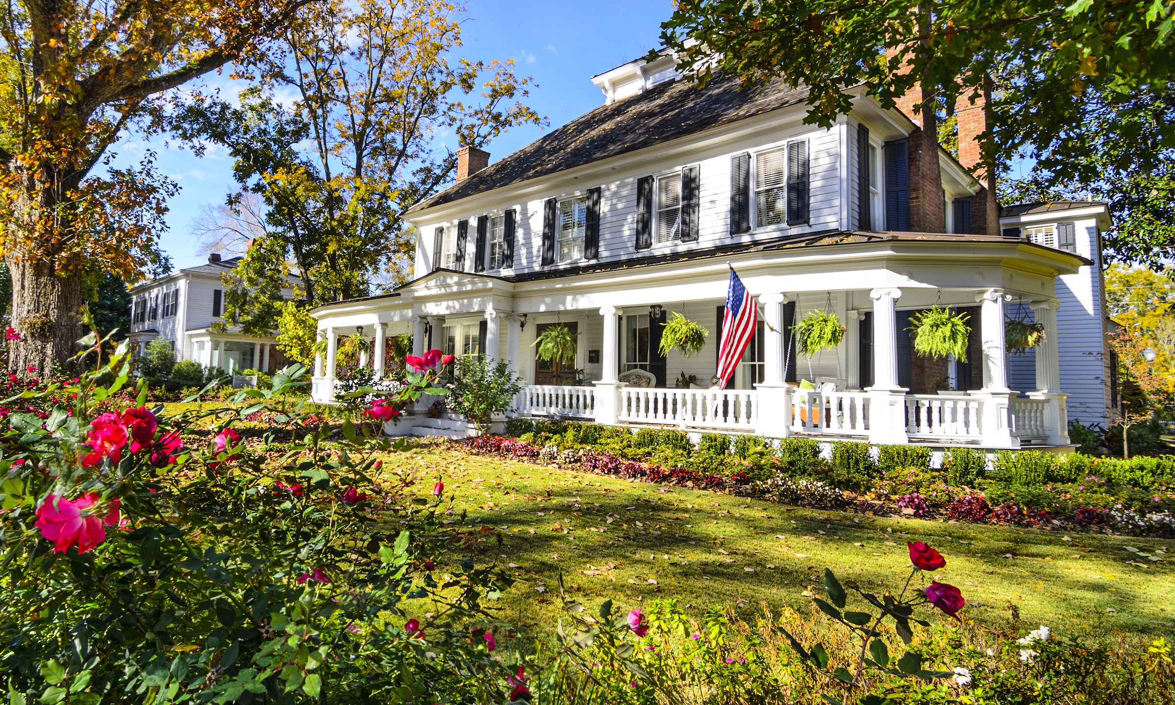 White Colonial House with Wrap-around Porch and Roses HD Wallpaper