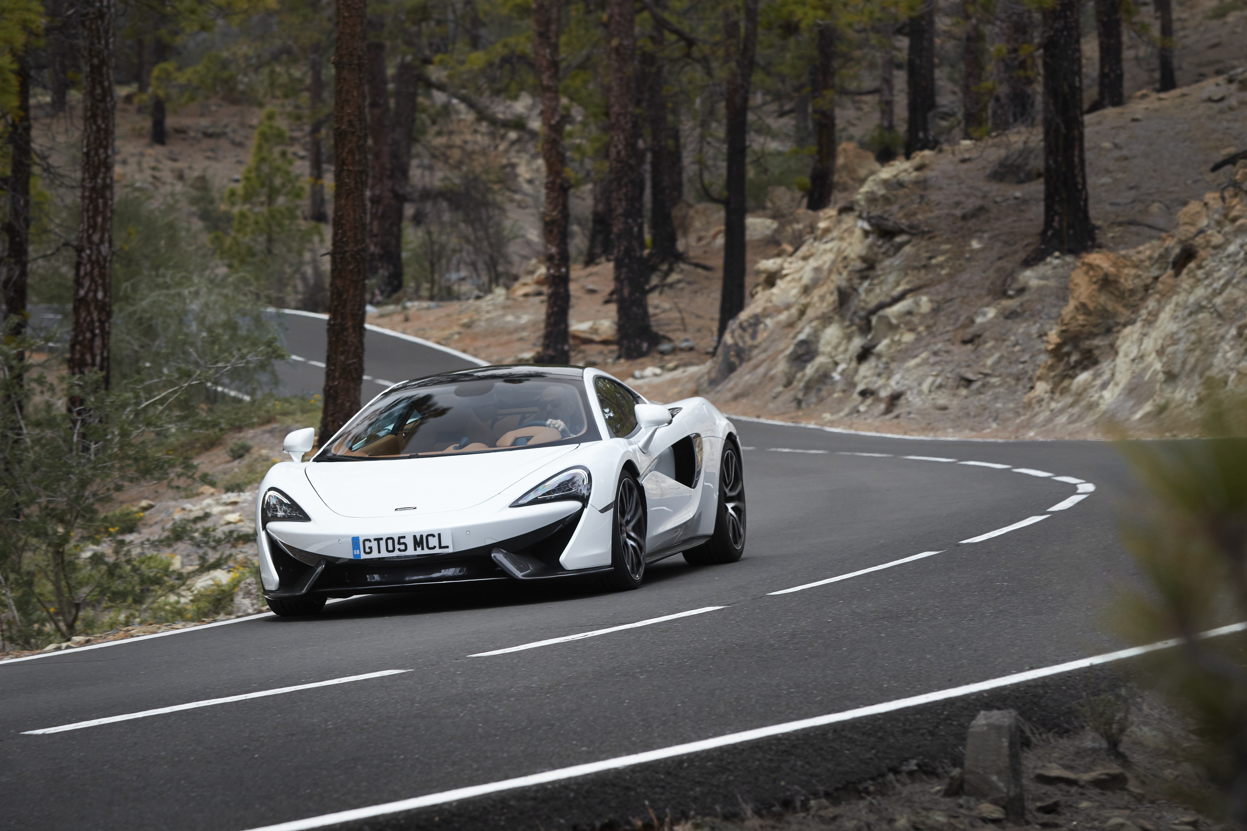 White McLaren 570GT driving on a mountain road HD Wallpaper