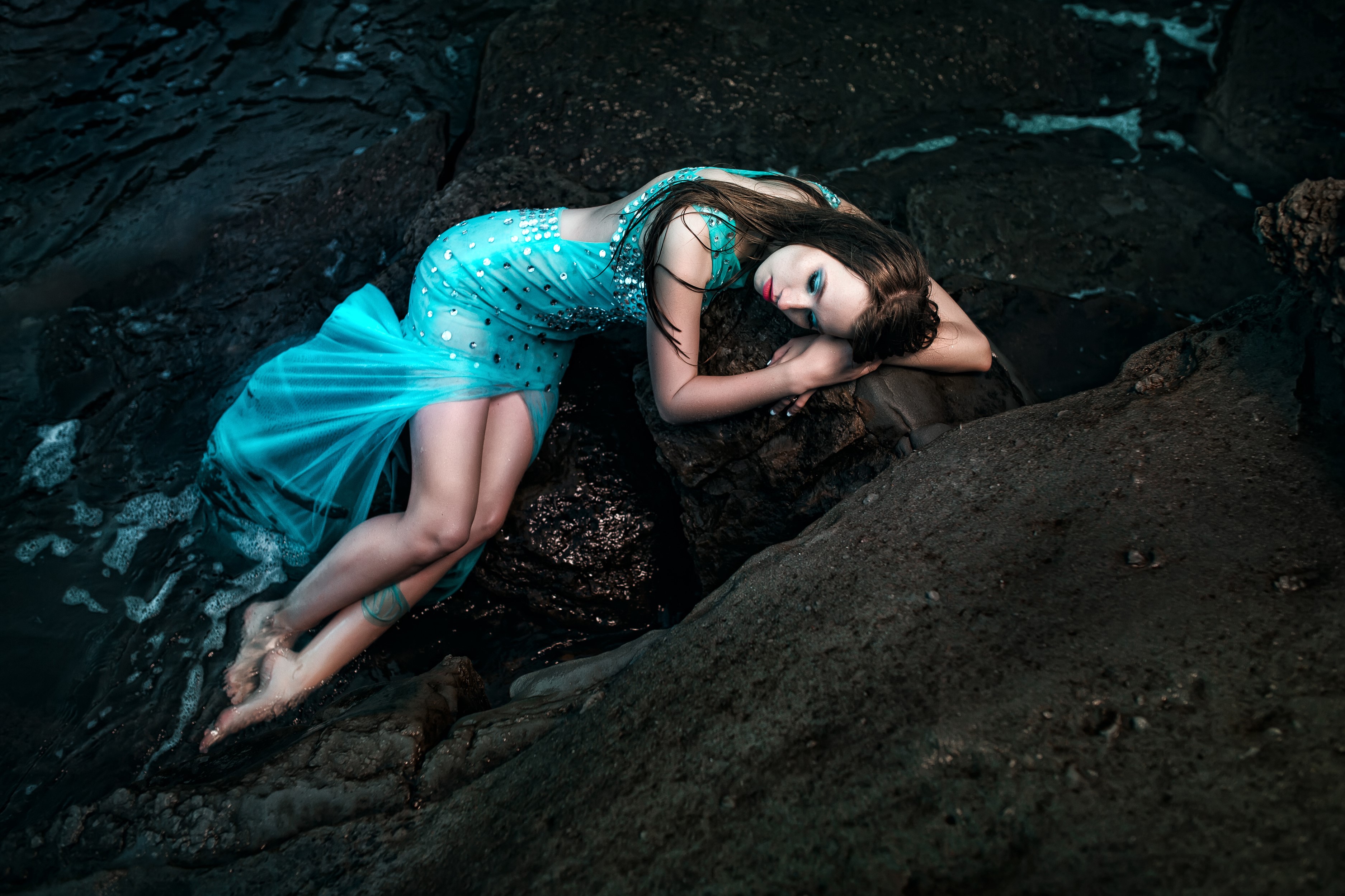 Woman in a blue dress lying on rocks by the water HD Wallpaper