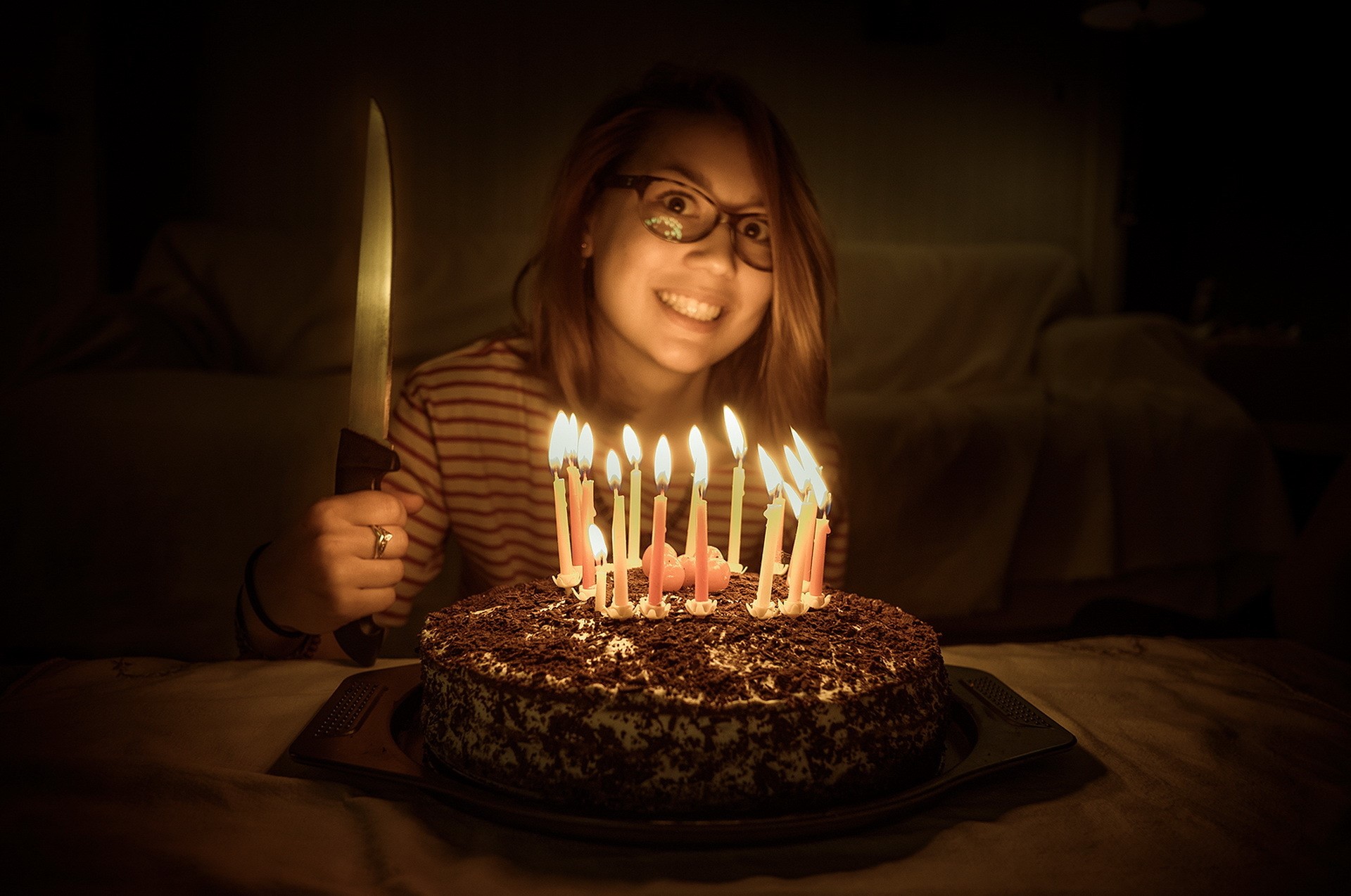 Woman holding a knife near a birthday cake with candles HD Wallpaper