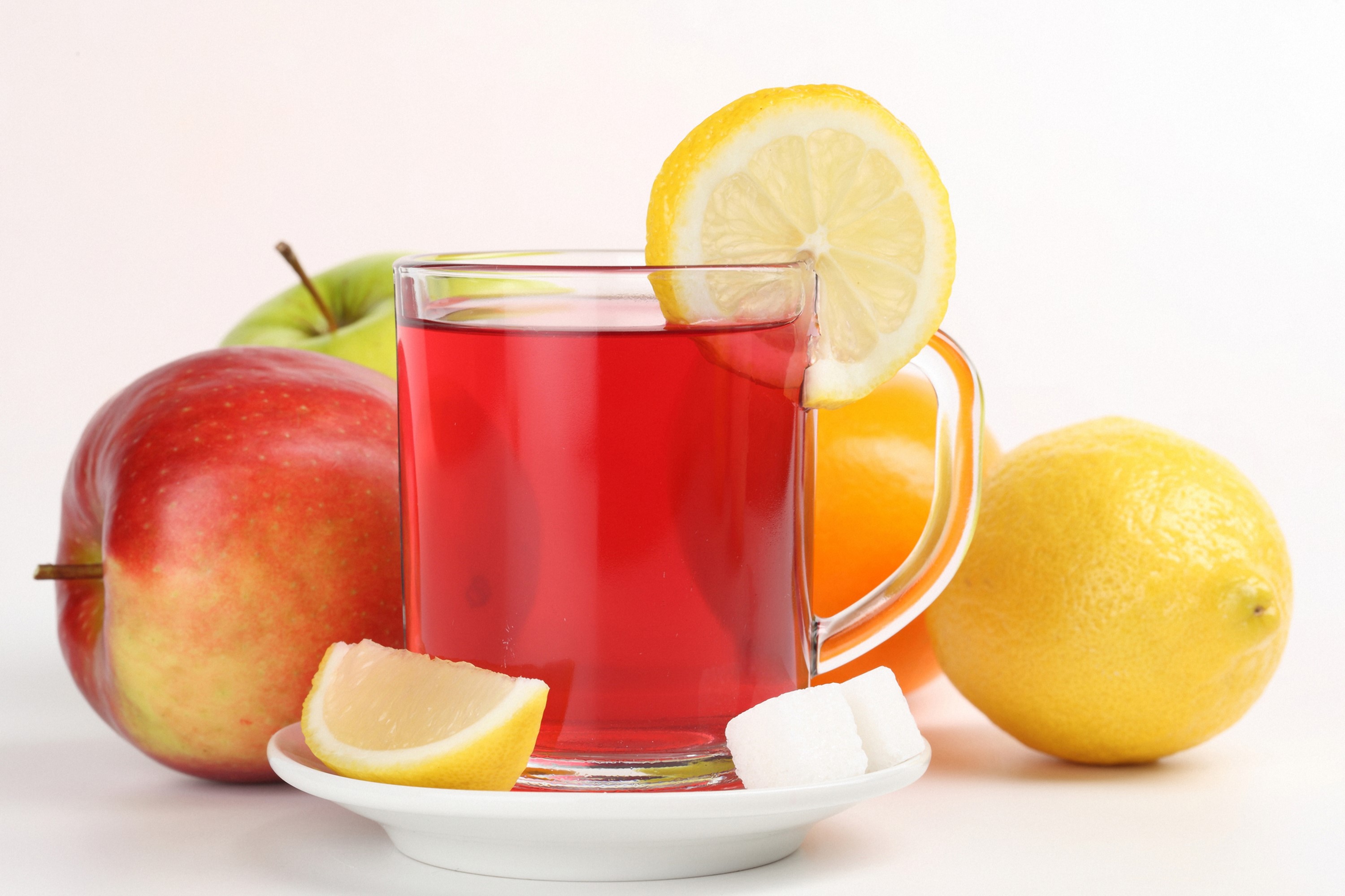 Glass of red tea with apples, lemons, and sugar cubes HD Wallpaper