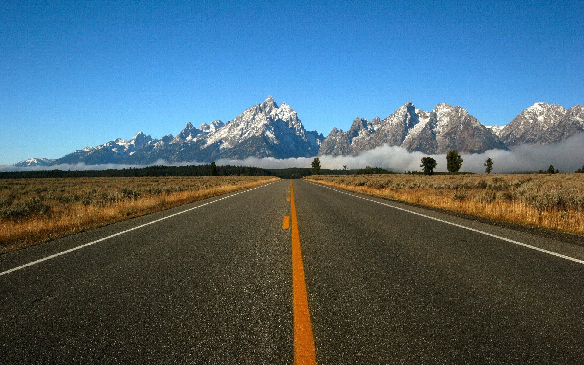 Road leading to snow-capped mountains and clouds HD Wallpaper