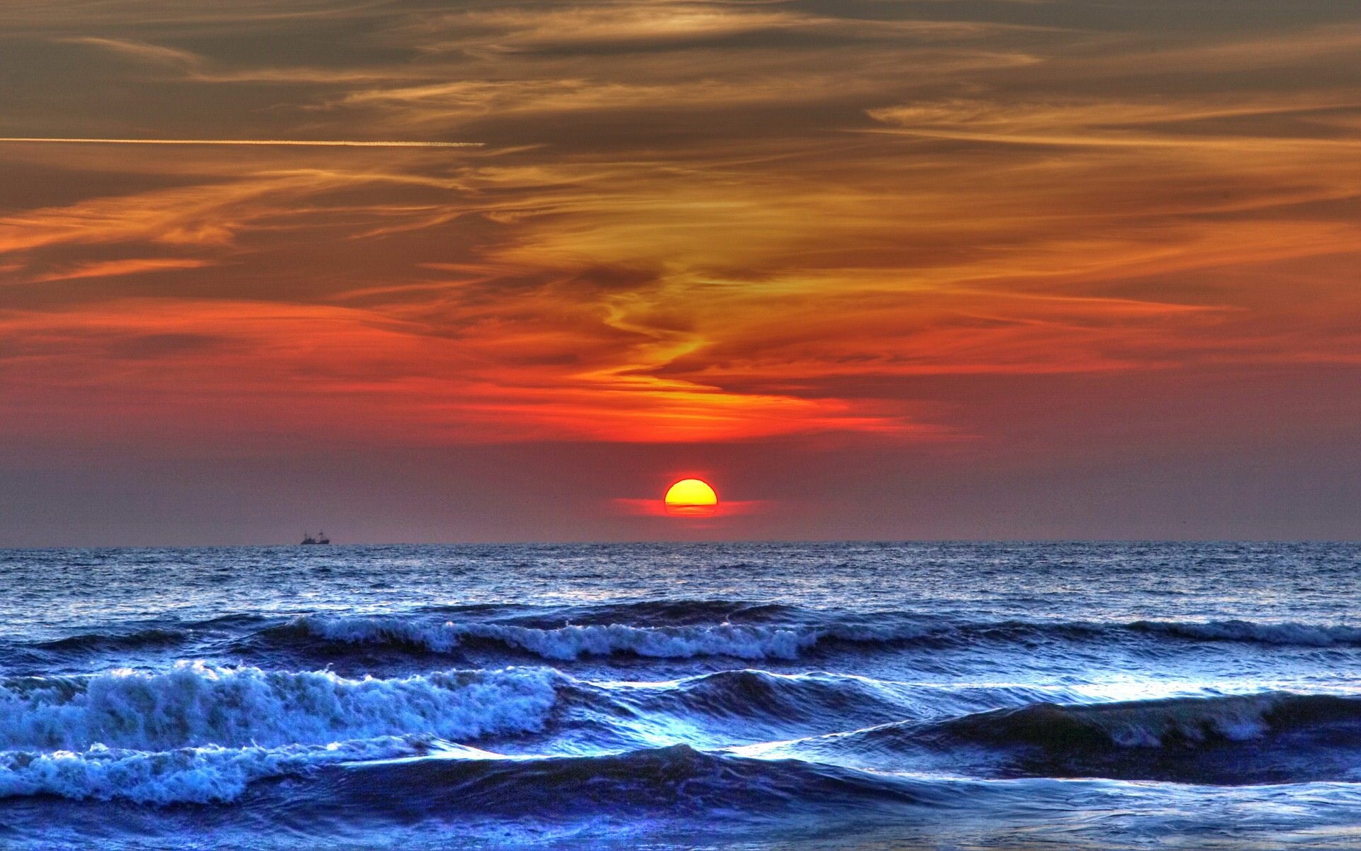 Sunset over the ocean with waves and a distant boat HD Wallpaper