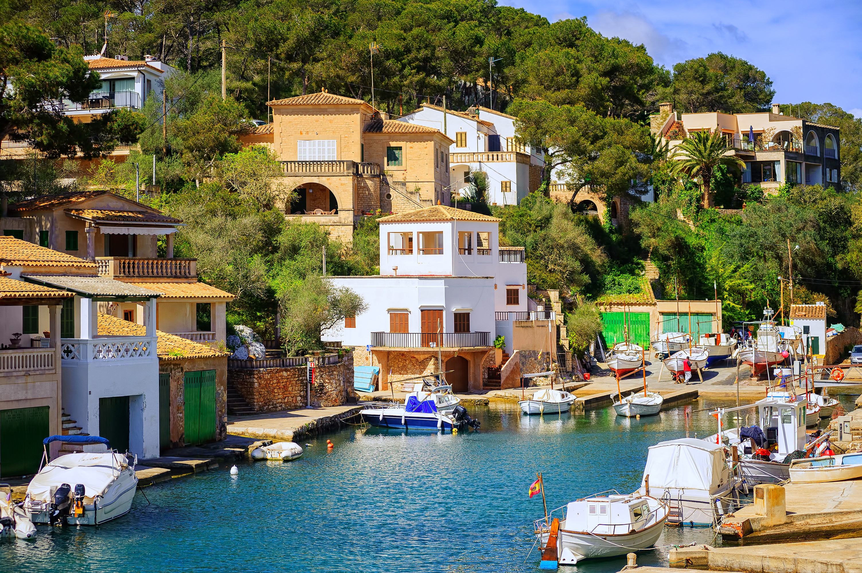 Boats docked in a harbor with houses on a hillside in Spain HD Wallpaper