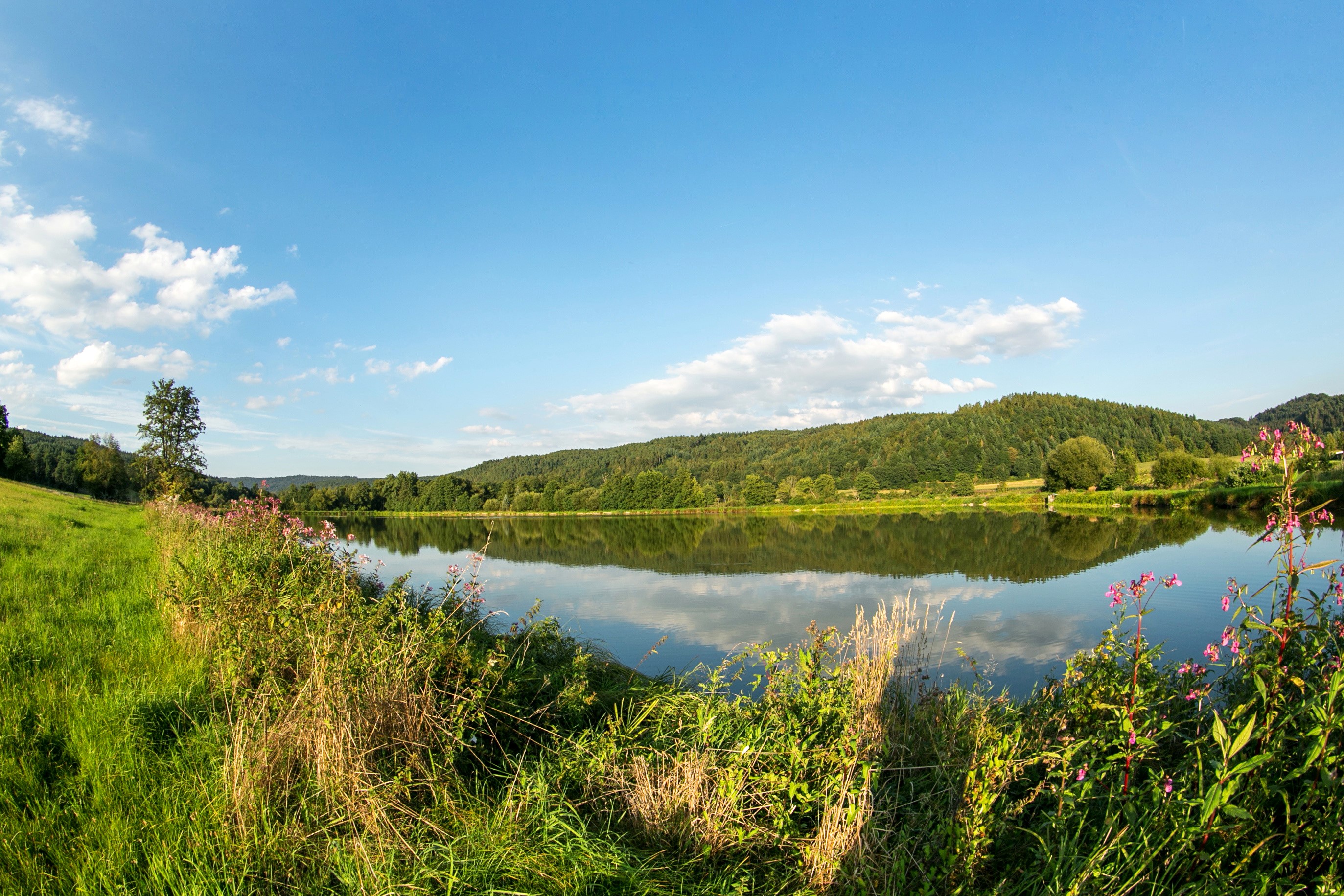 Lake and green hills under a blue sky with clouds in Brandenburg, Germany HD Wallpaper
