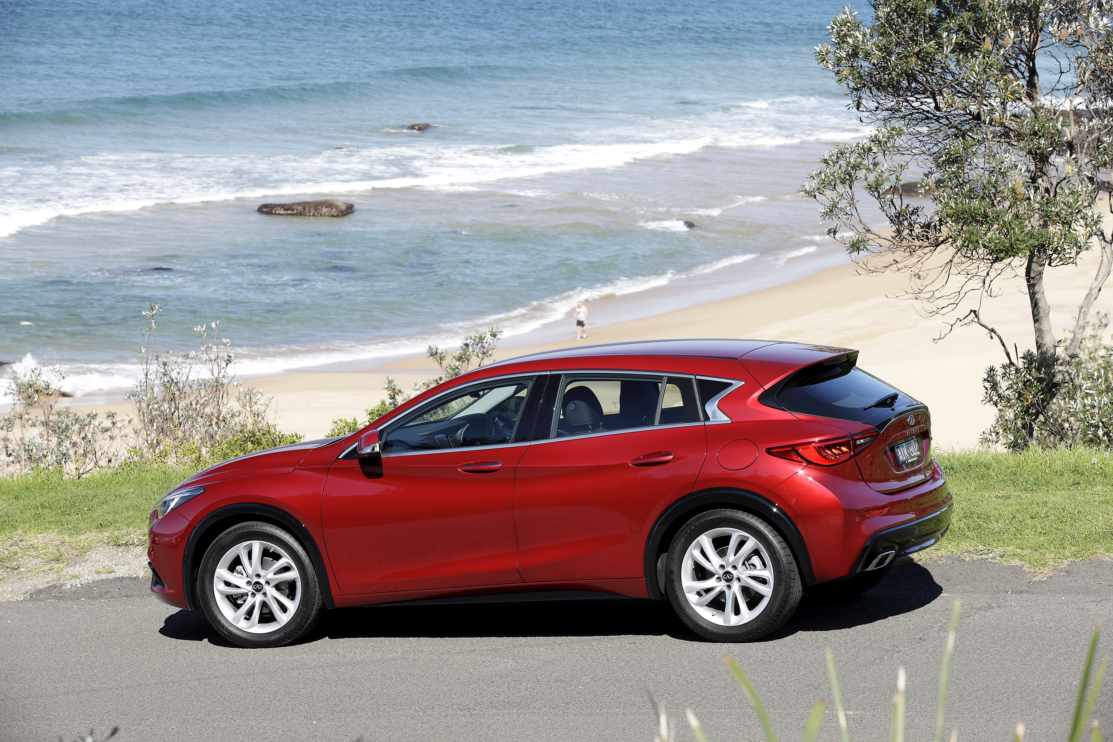 Red Infiniti Q30 parked by the ocean HD Wallpaper