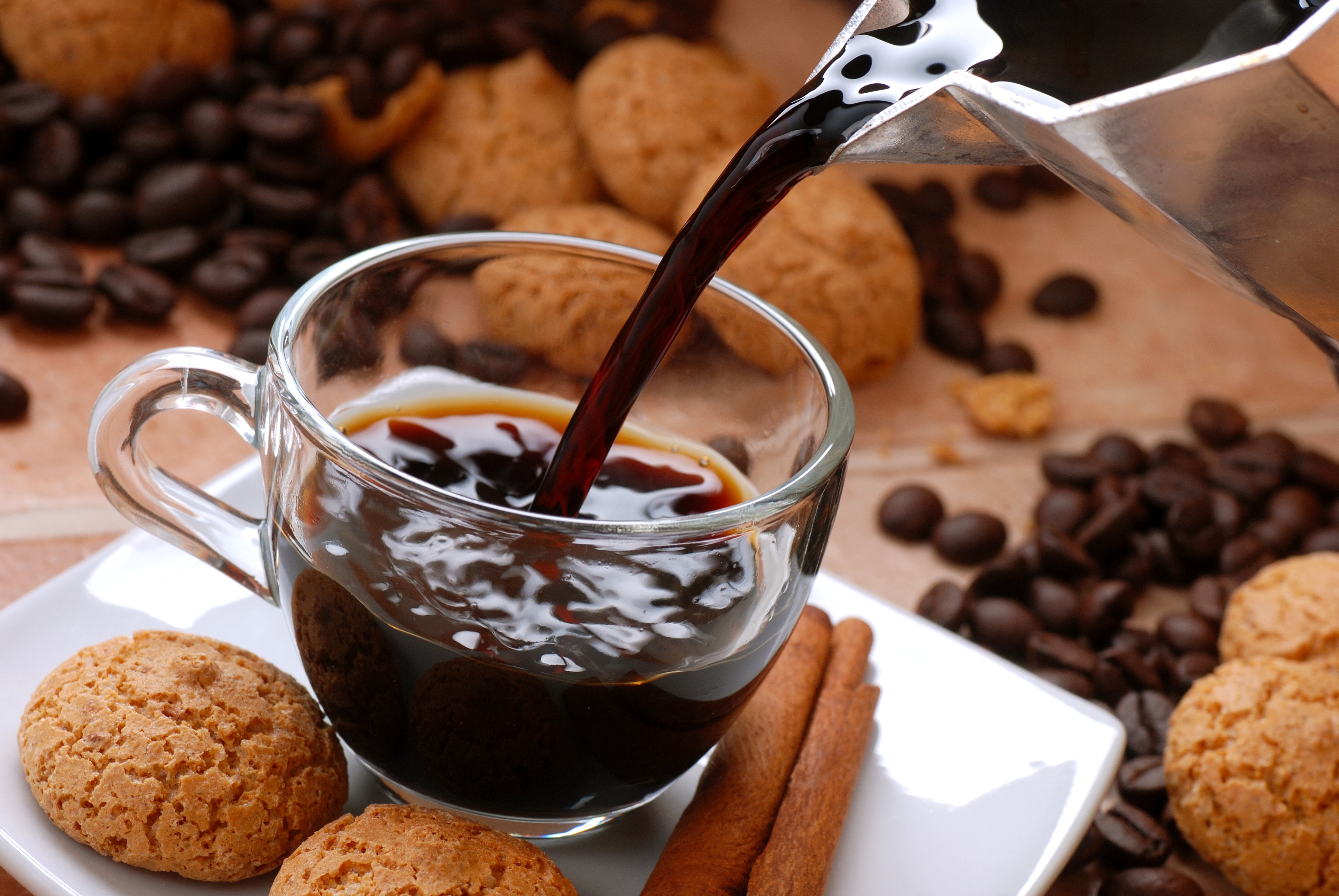 Coffee poured into a cup with cookies and cinnamon sticks HD Wallpaper