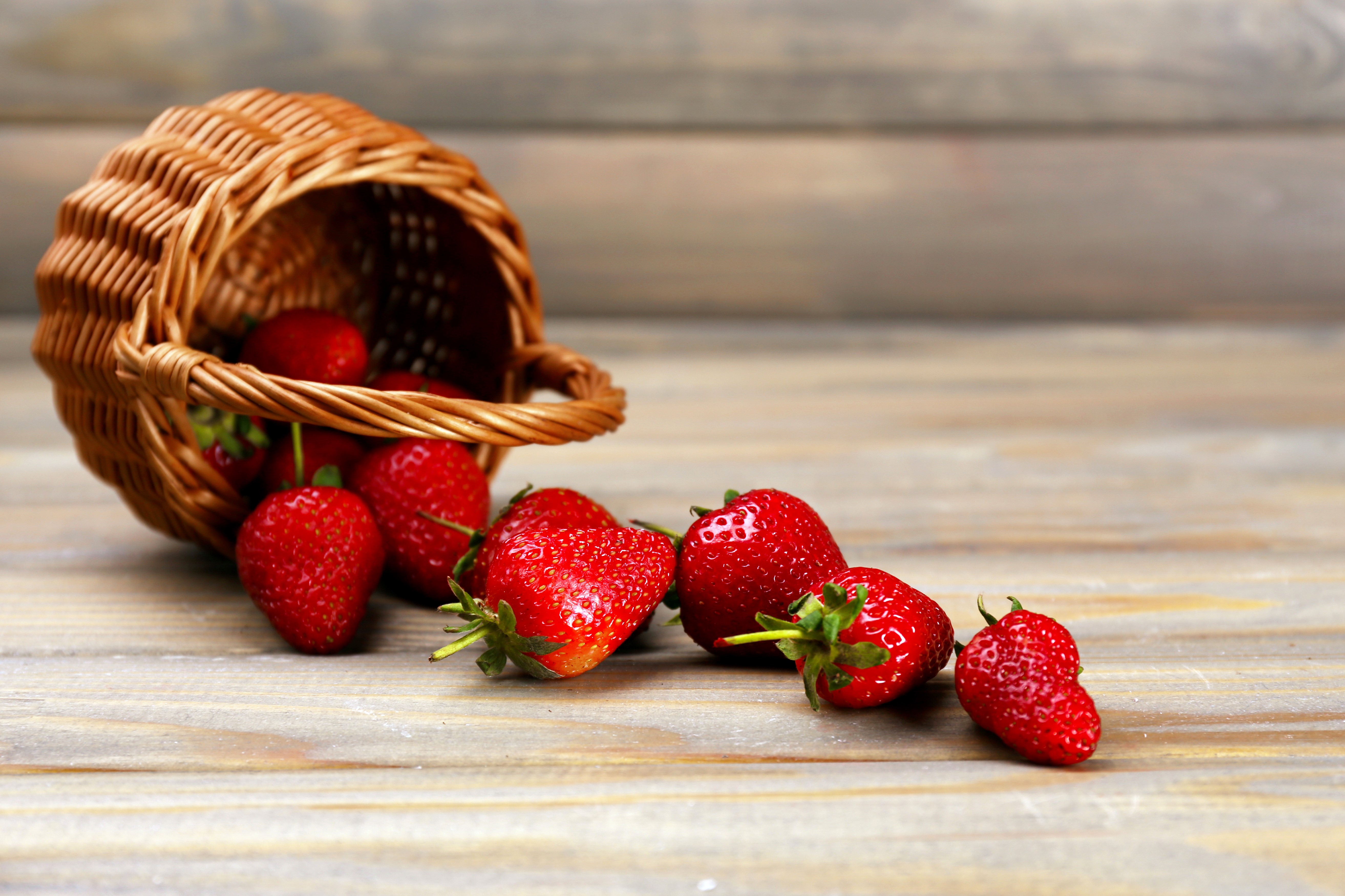 Strawberries spilling from a wicker basket HD Wallpaper