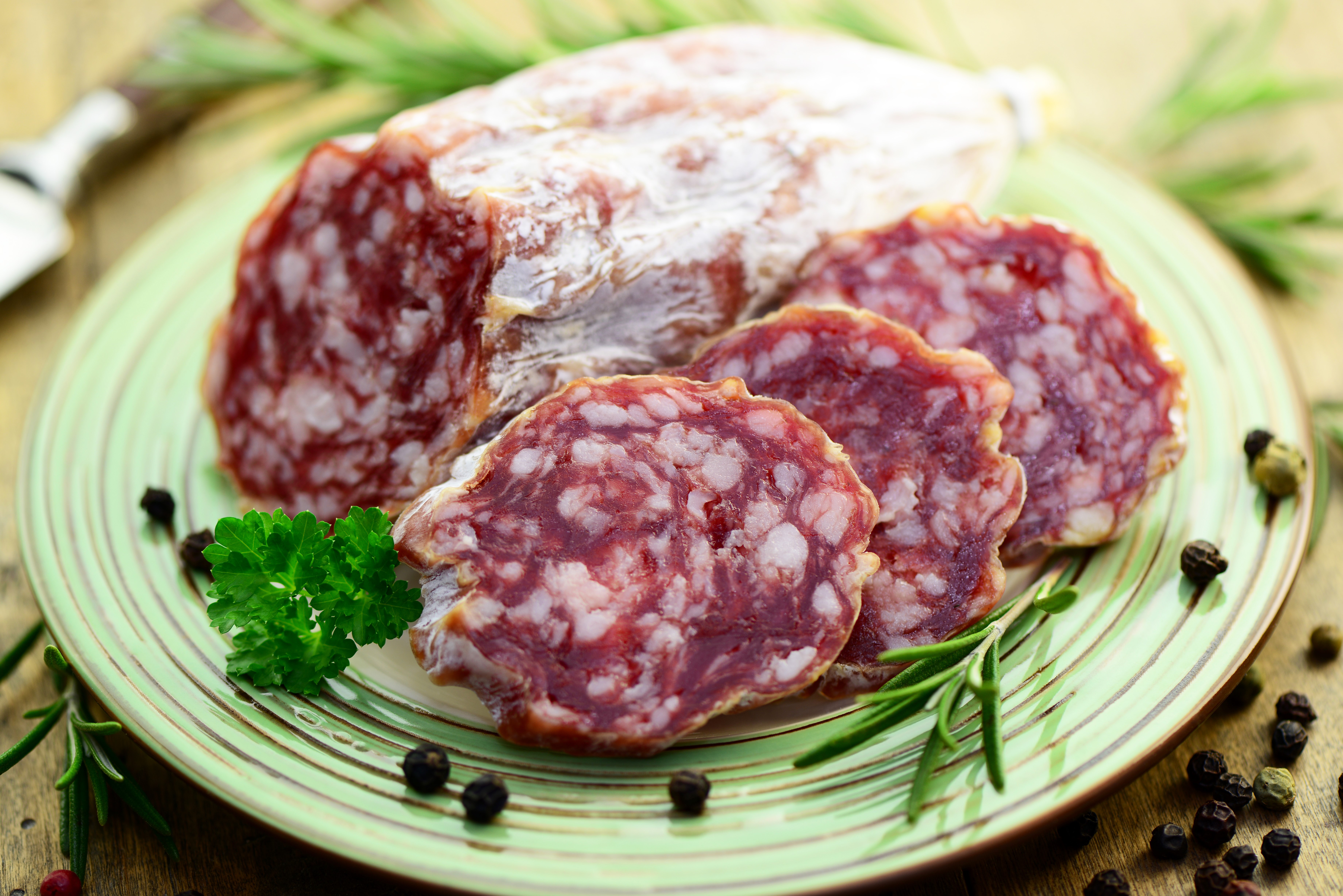 Sausage slices on a plate with rosemary and peppercorns HD Wallpaper