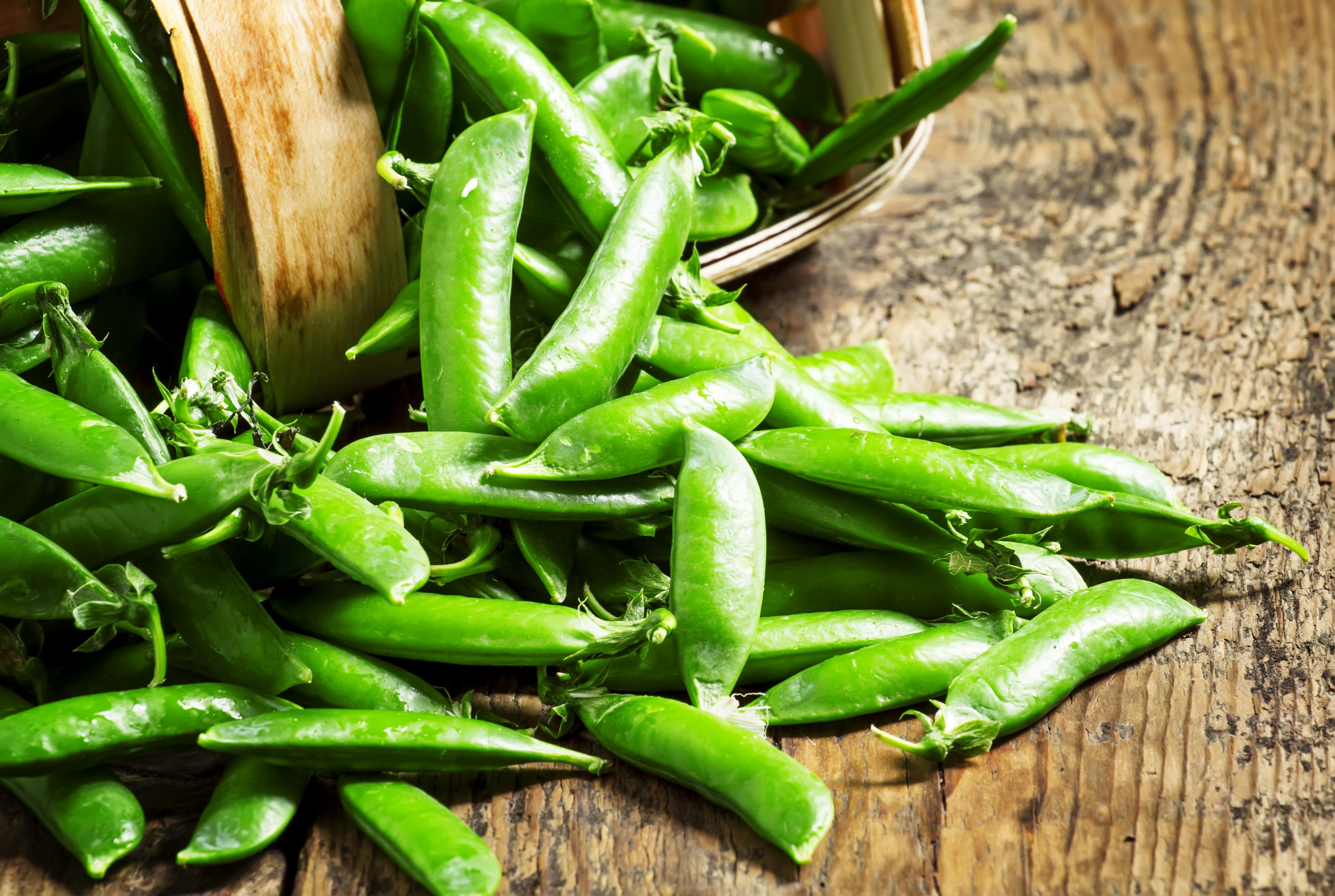 Green peas in a basket on a wooden table HD Wallpaper