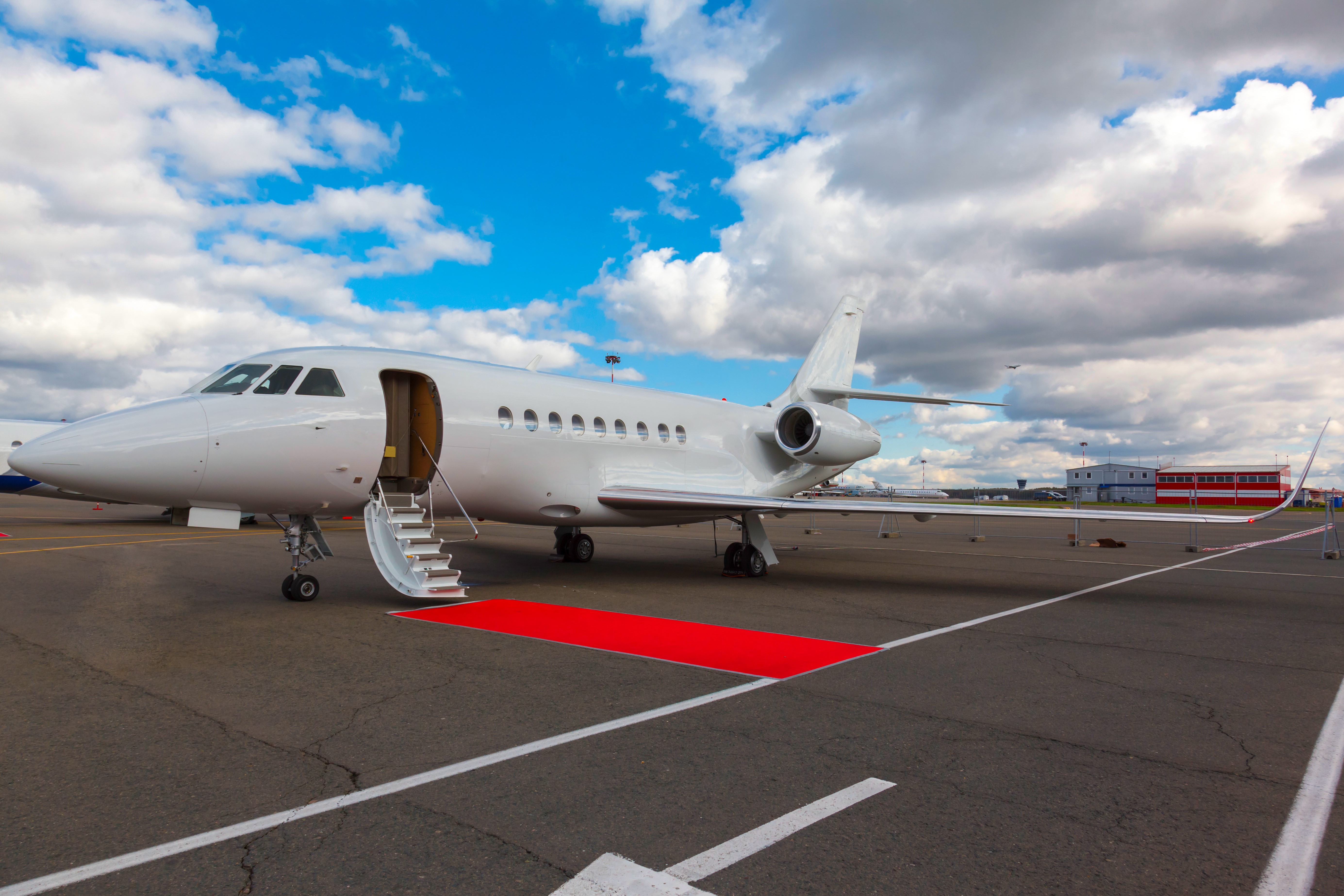 Private jet with open door and red carpet on tarmac HD Wallpaper