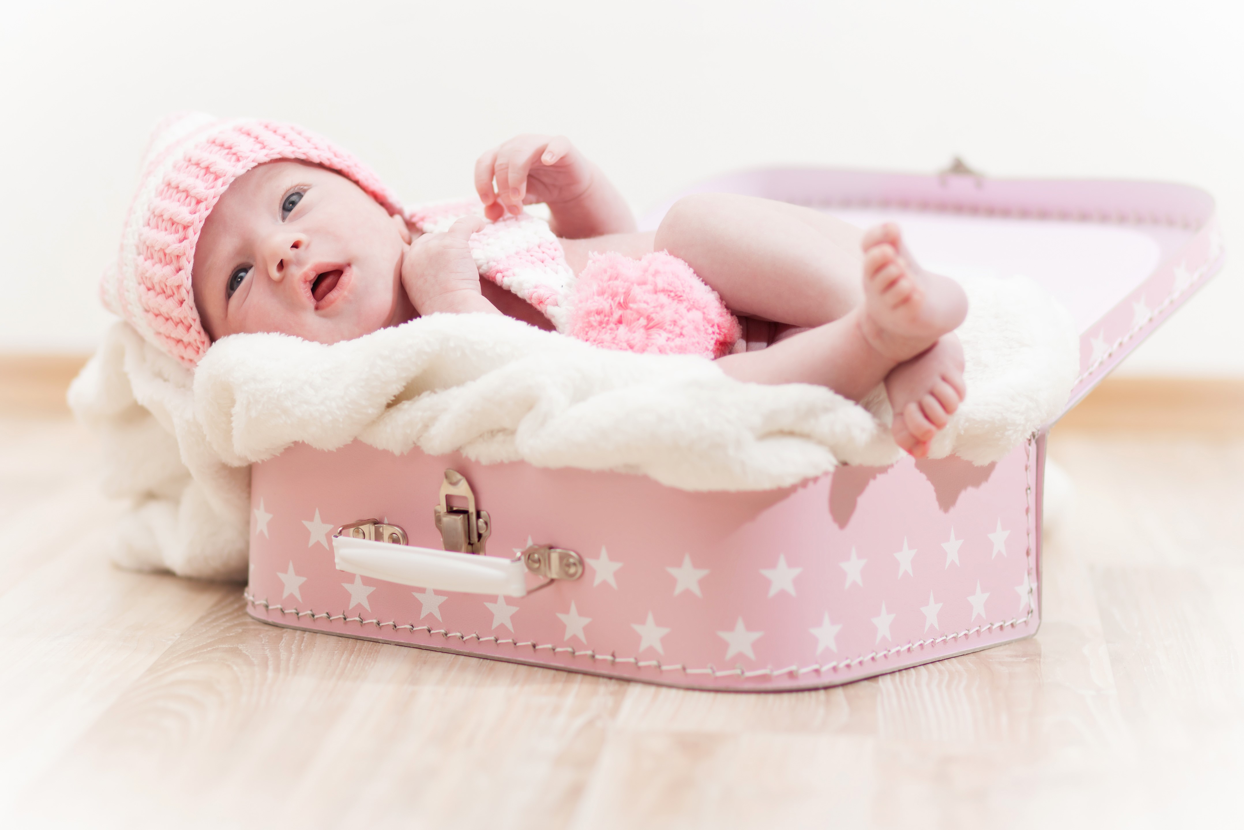 Infant in a pink suitcase with a winter hat HD Wallpaper