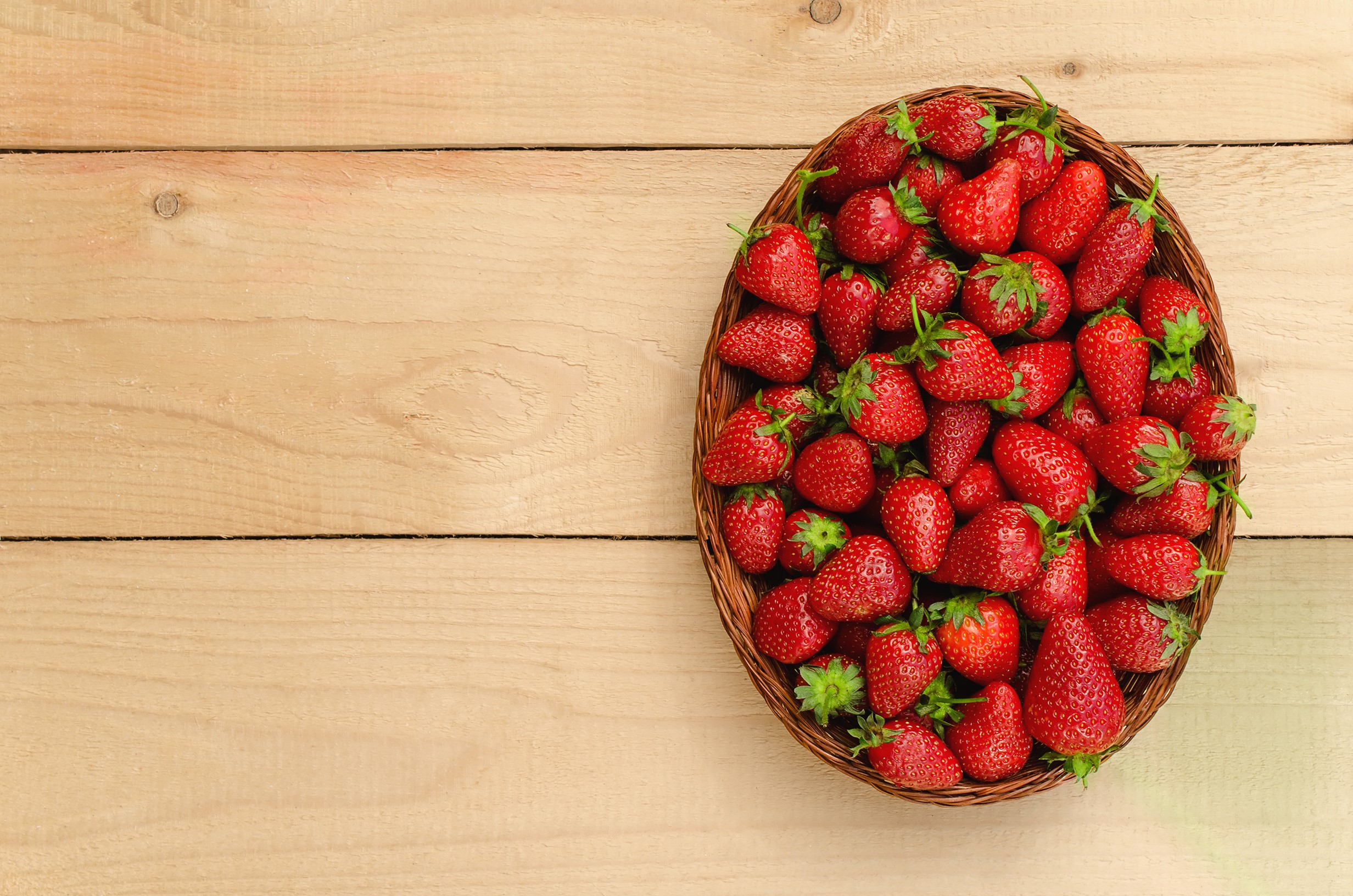 Basket of fresh strawberries on a wooden table HD Wallpaper