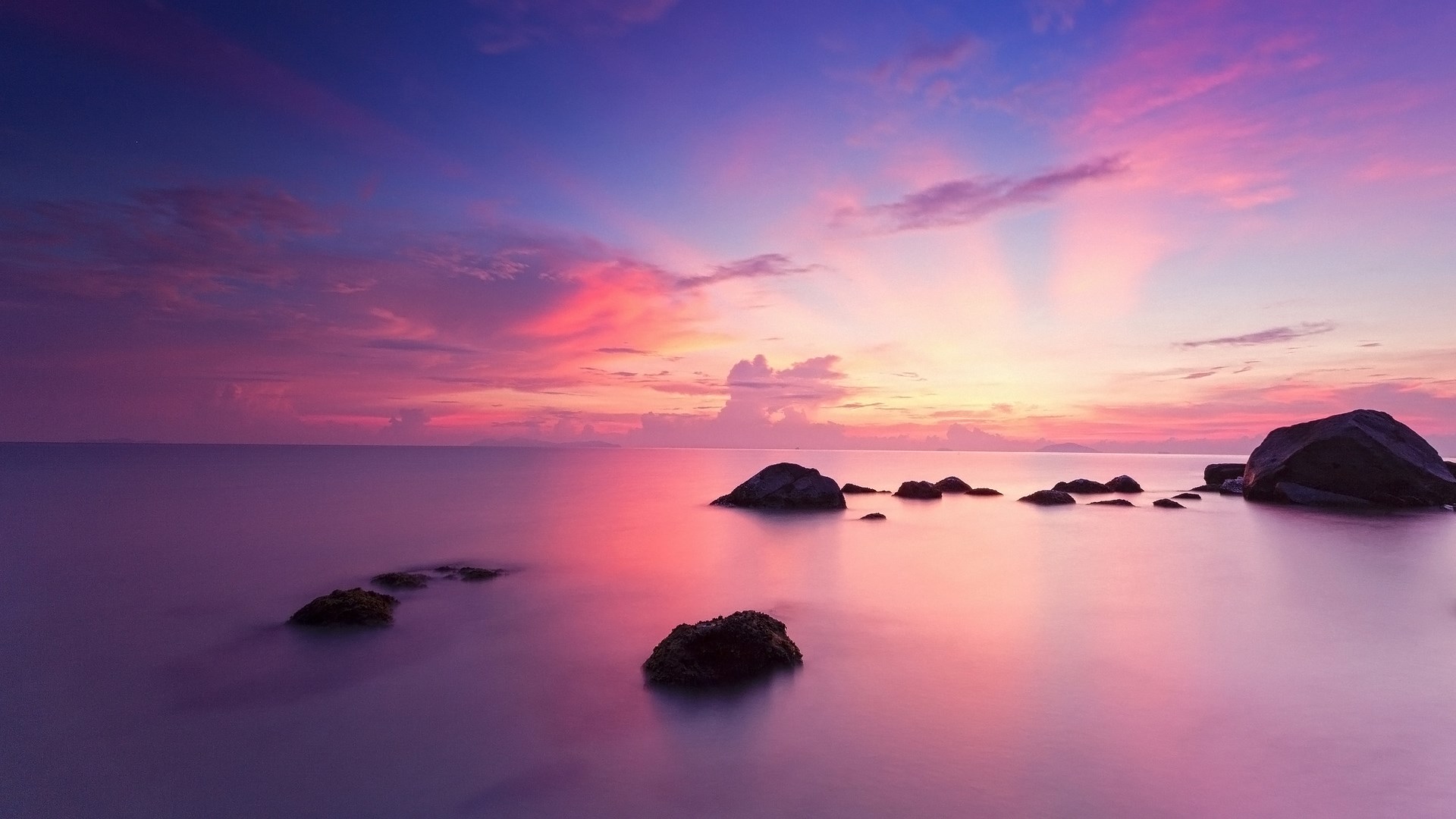Ocean sunset with pink and purple clouds and rocks HD Wallpaper