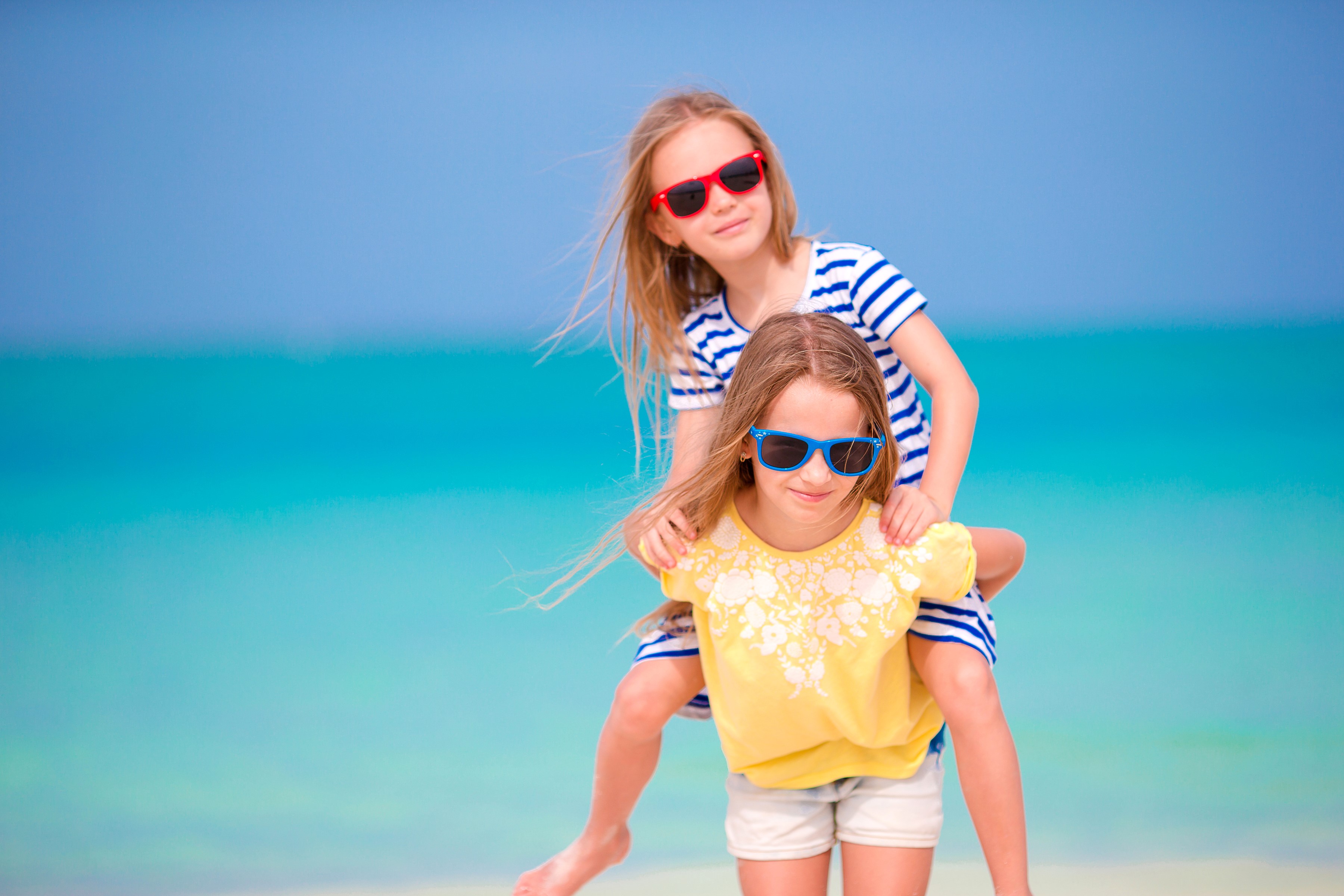 Two young girls wearing sunglasses on a beach HD Wallpaper