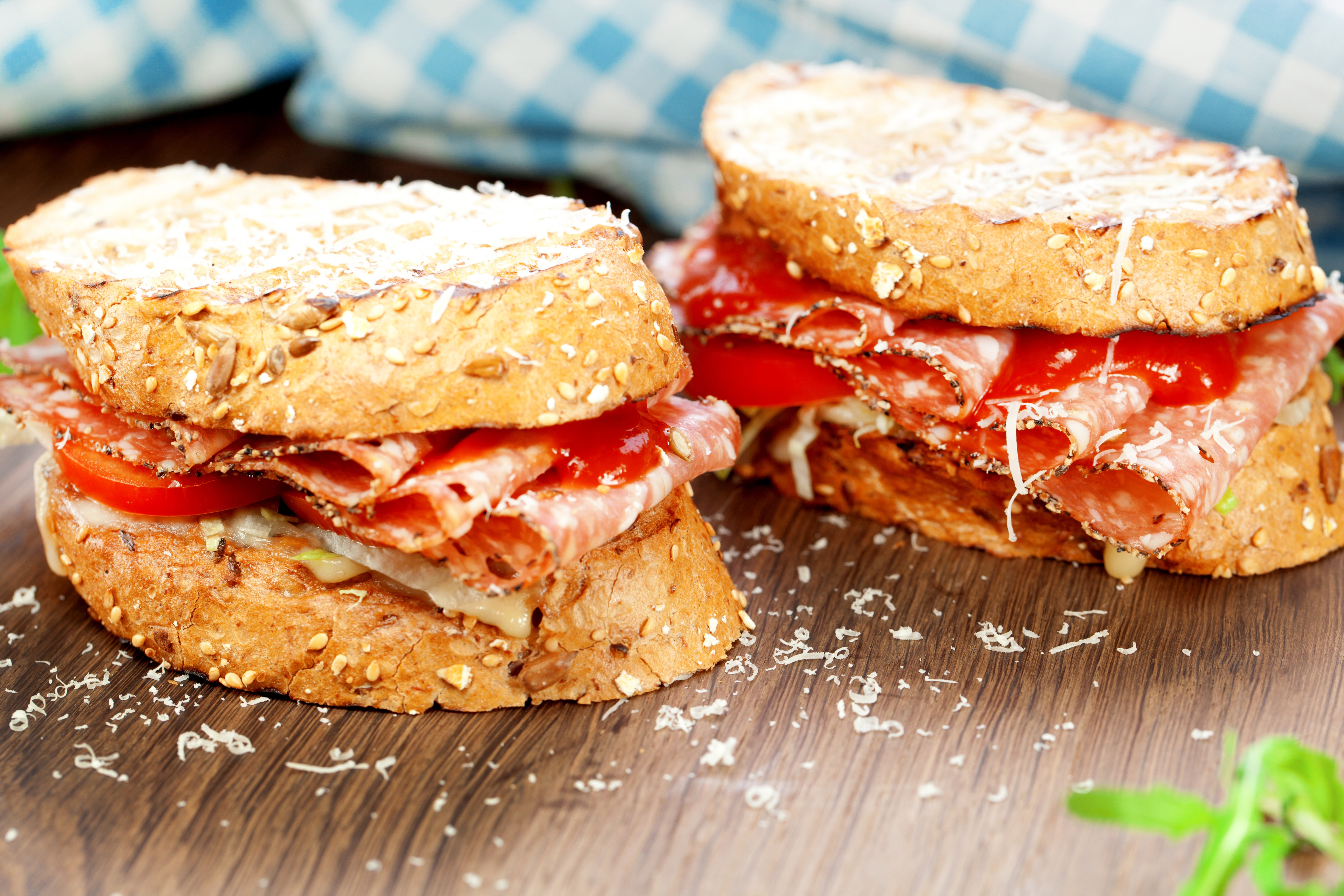 Two sandwiches with salami and tomato on wooden table HD Wallpaper