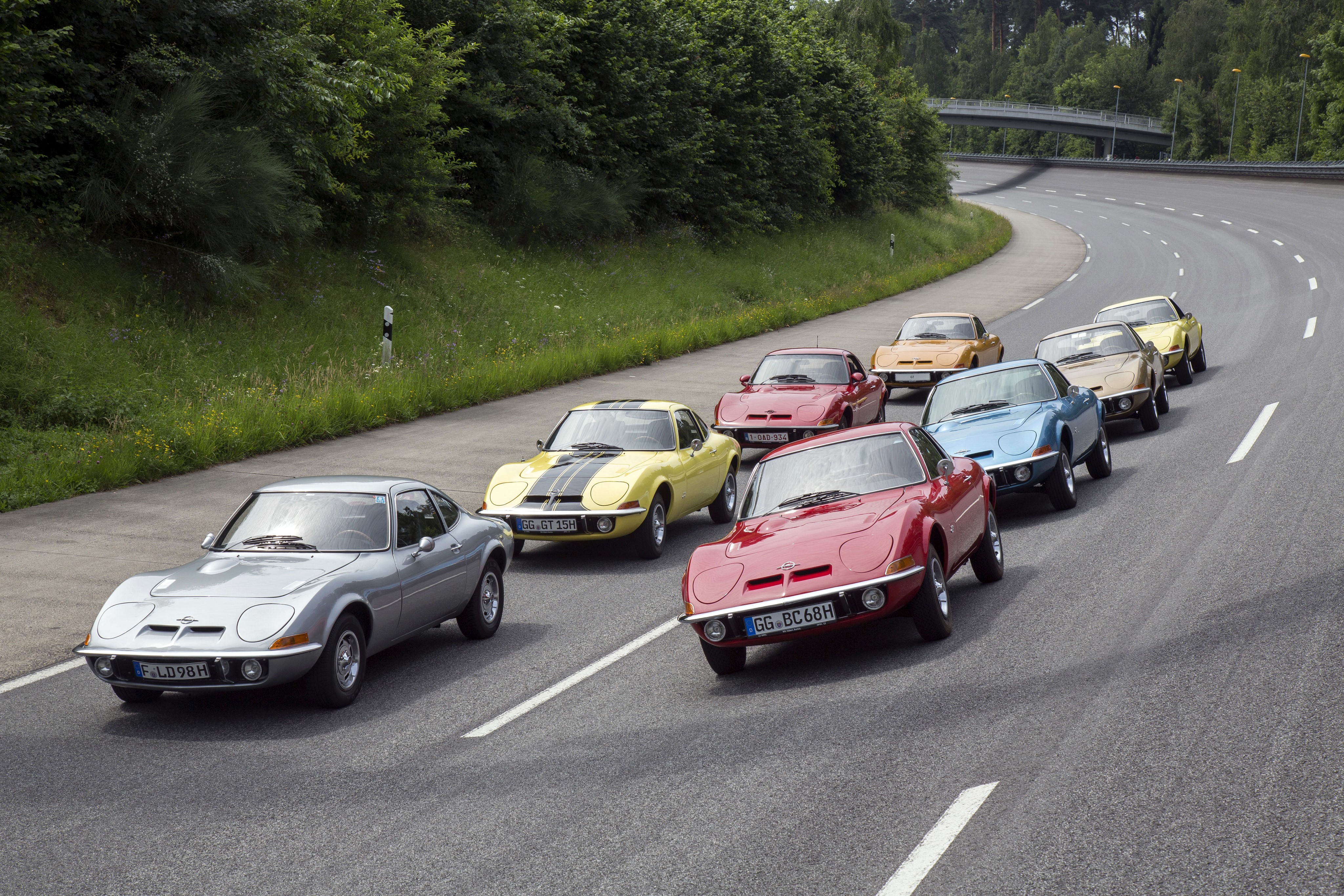 Multiple Opel GT cars driving on a road HD Wallpaper