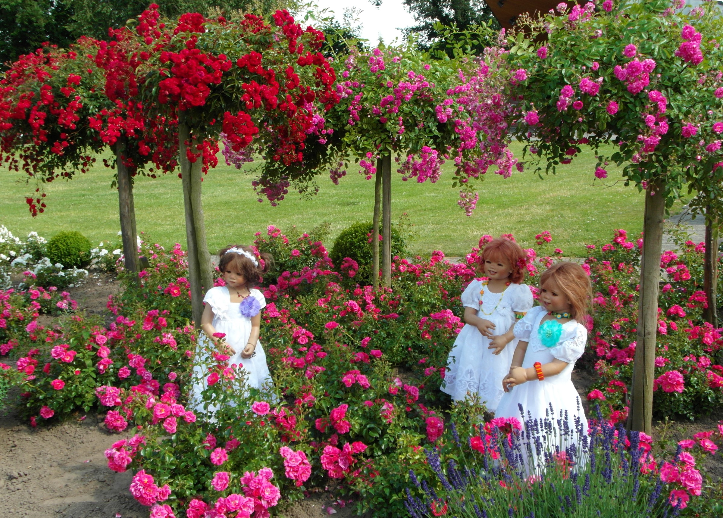 Three dolls in a rose garden at Grugapark Essen HD Wallpaper
