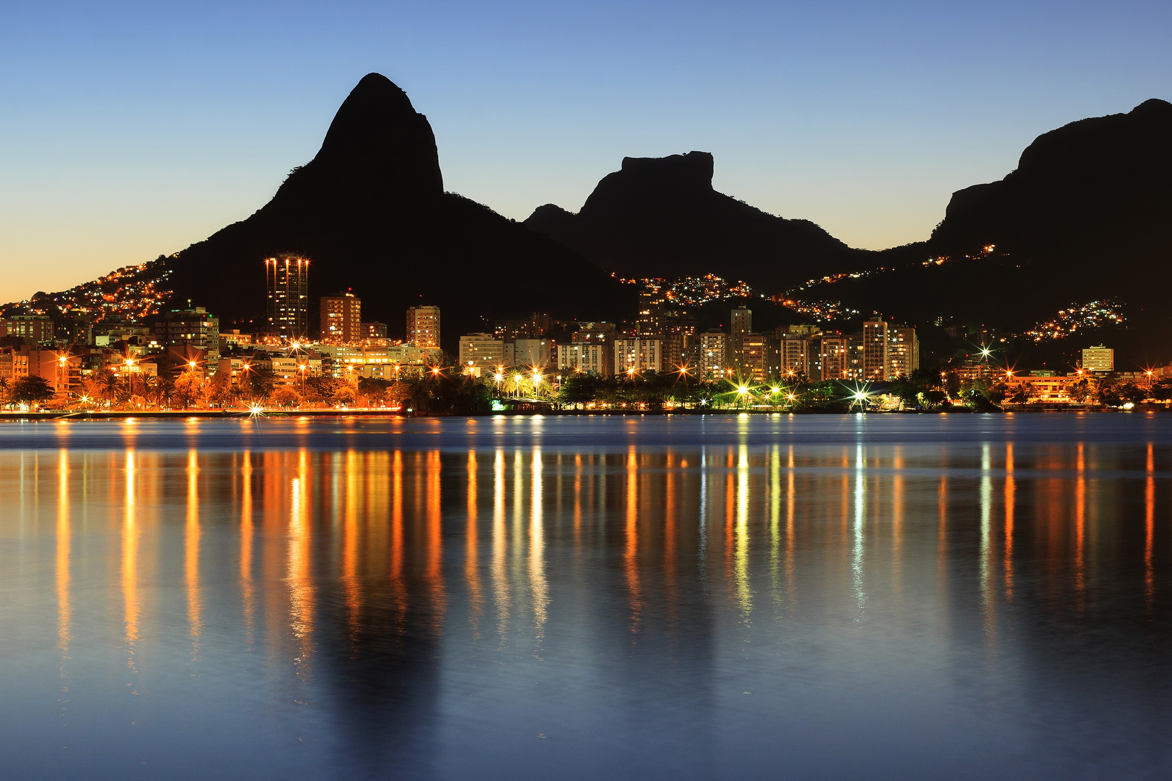 Rio de Janeiro skyline at night with mountains and water reflection HD Wallpaper