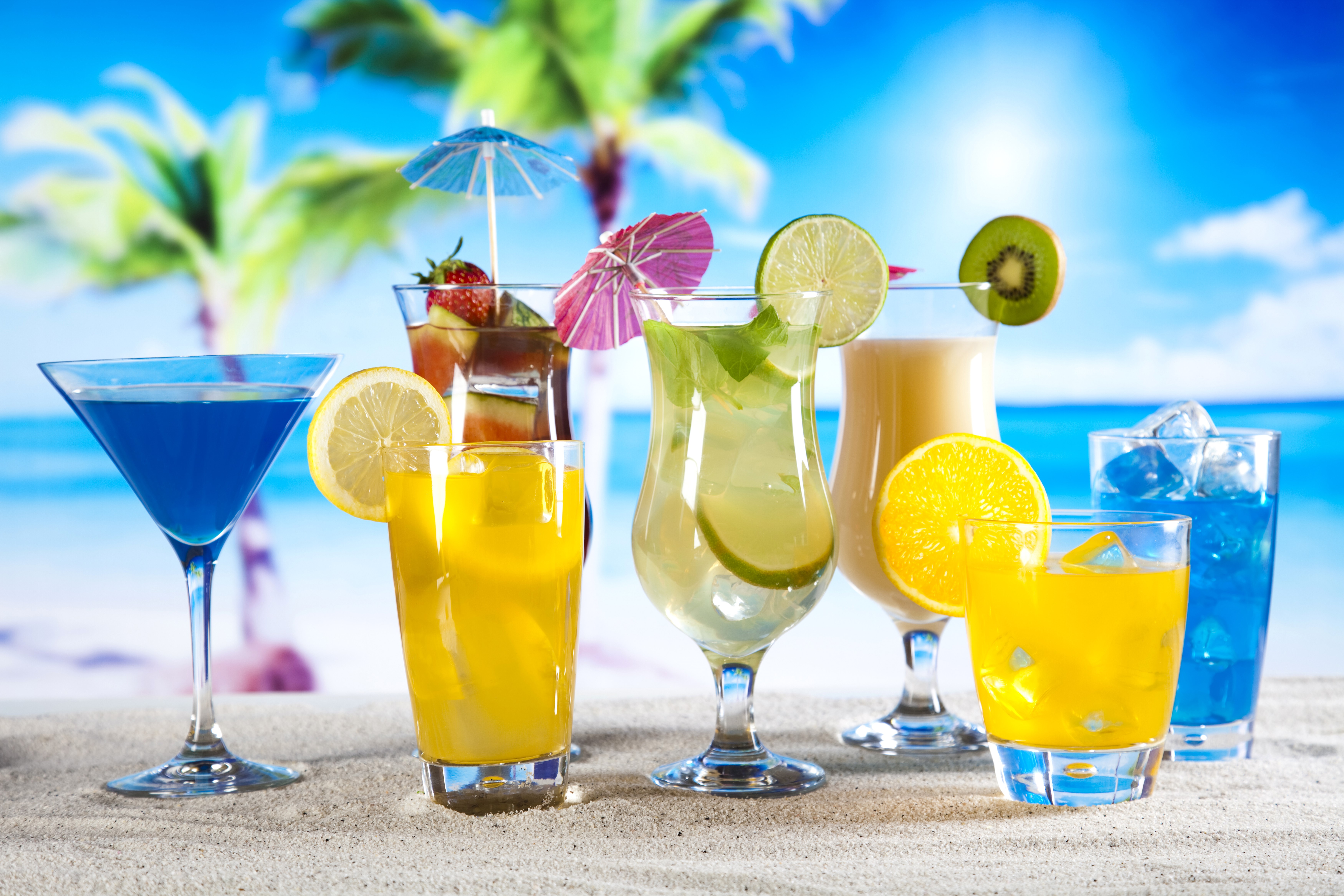Assorted tropical cocktails on a sandy beach HD Wallpaper