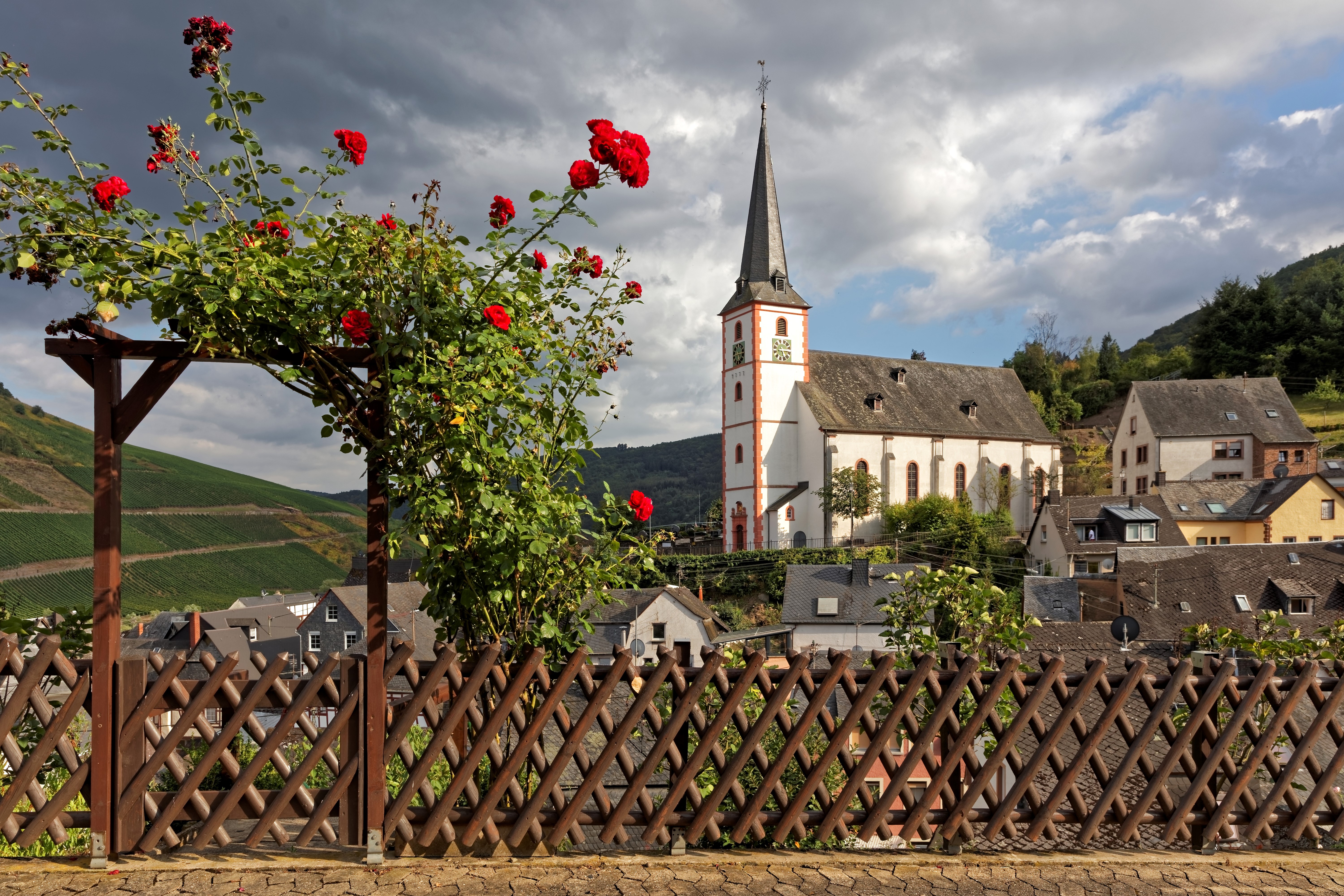 Church and houses in Briedel, Germany with roses and fence HD Wallpaper