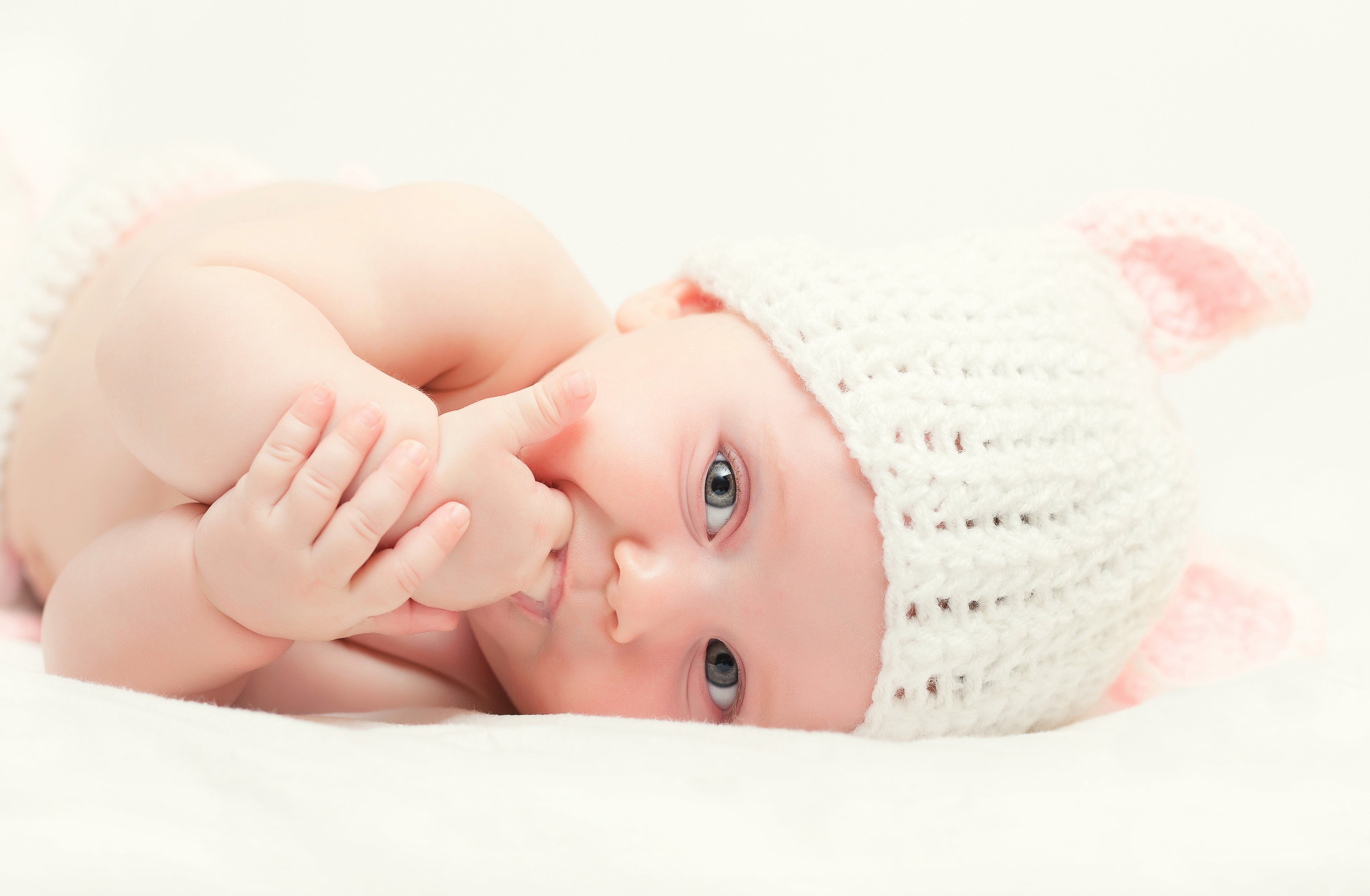 Baby wearing a white knitted hat with pink ears HD Wallpaper