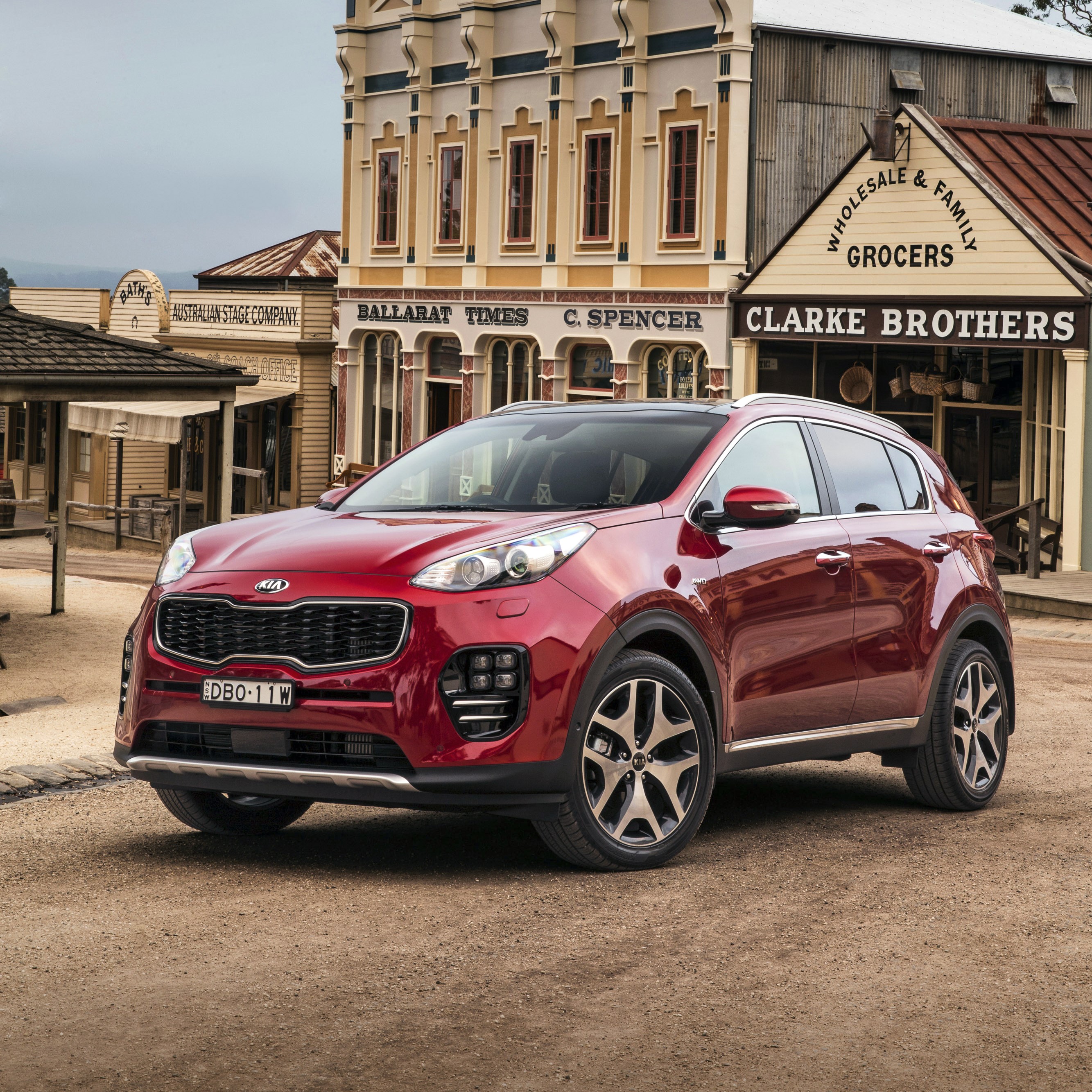 Red Kia Sportage in front of old buildings HD Wallpaper