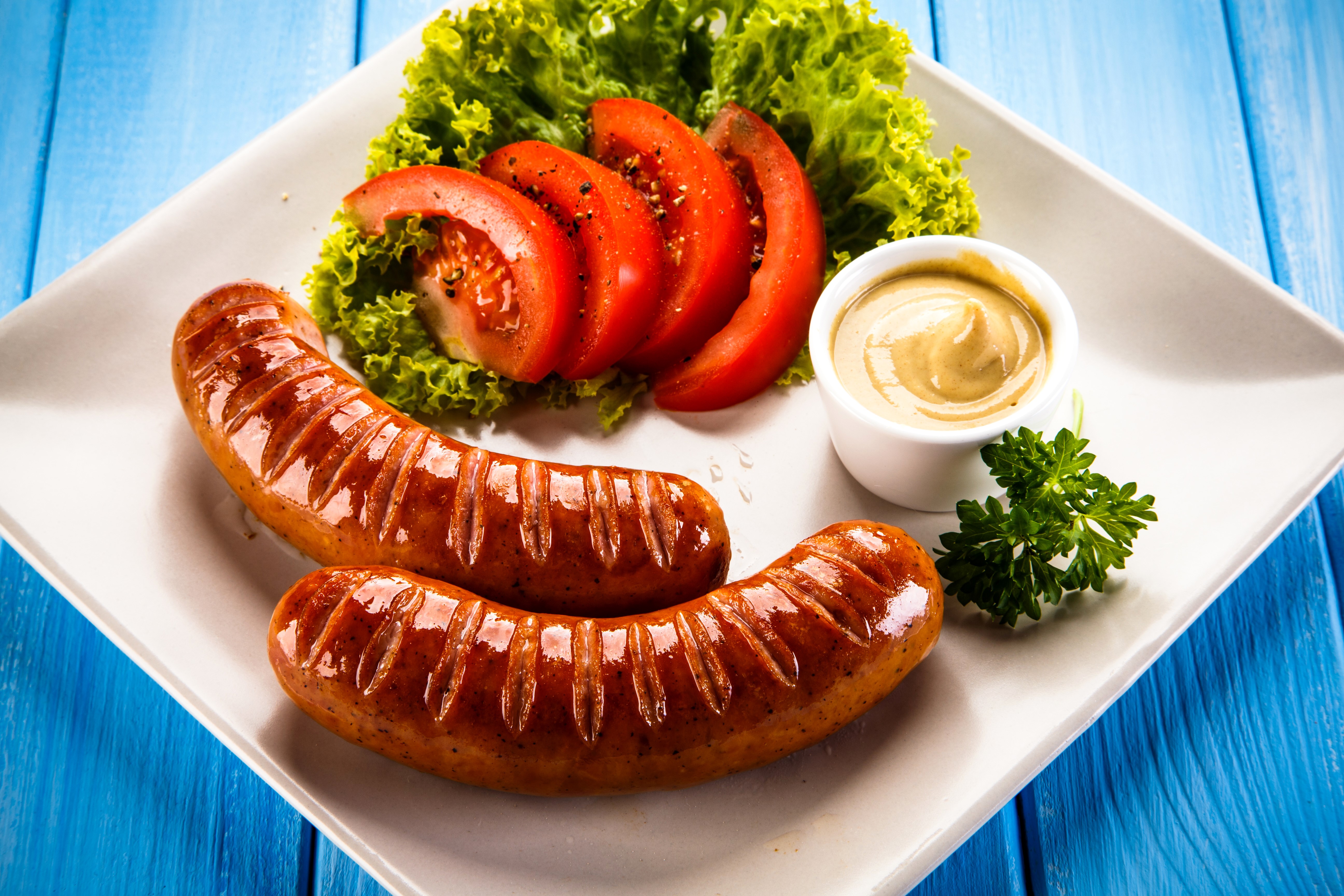 Two Vienna sausages with tomatoes, lettuce, and mustard HD Wallpaper