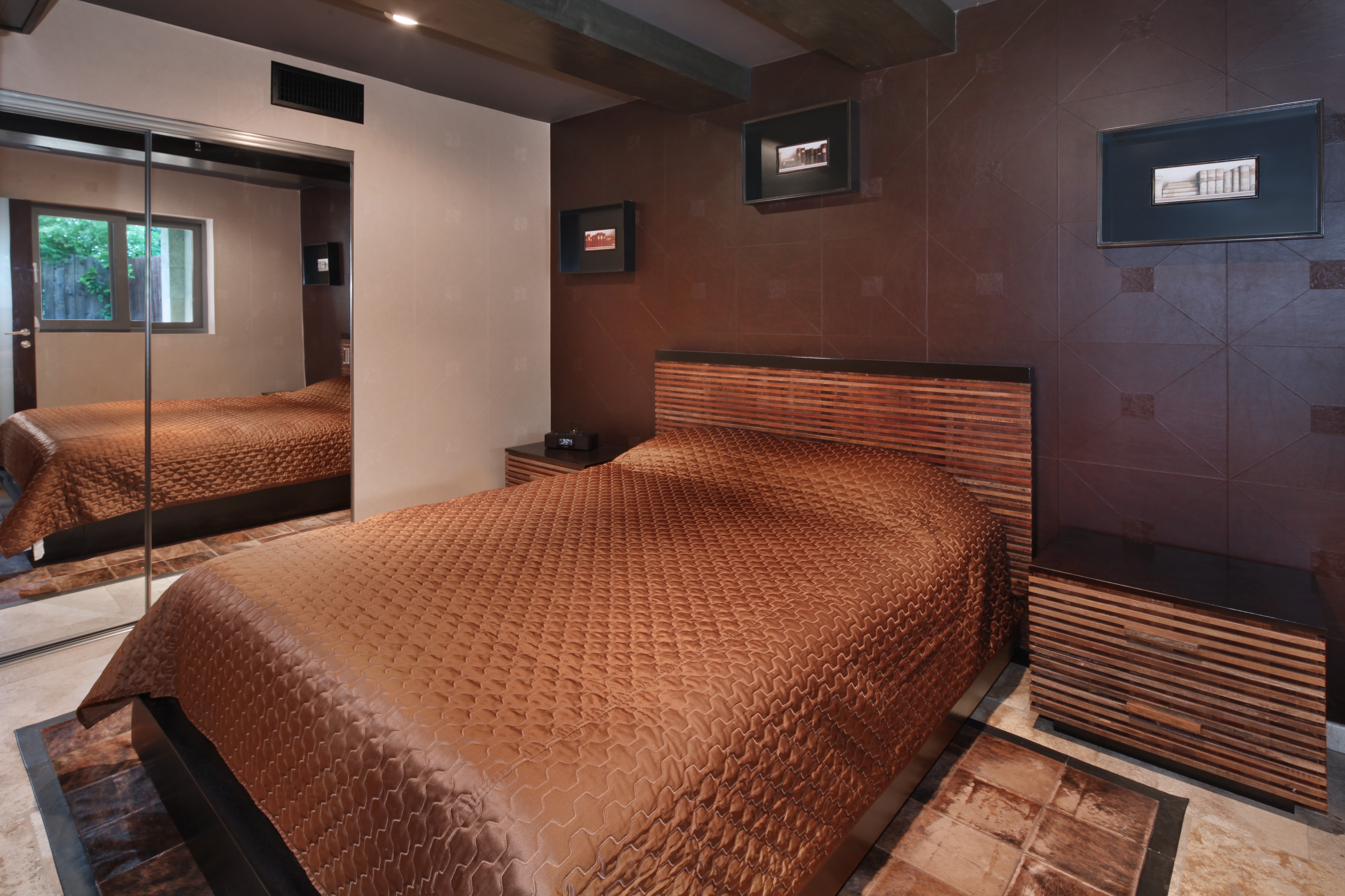 Bedroom with brown quilted bedspread and mirrored closet HD Wallpaper
