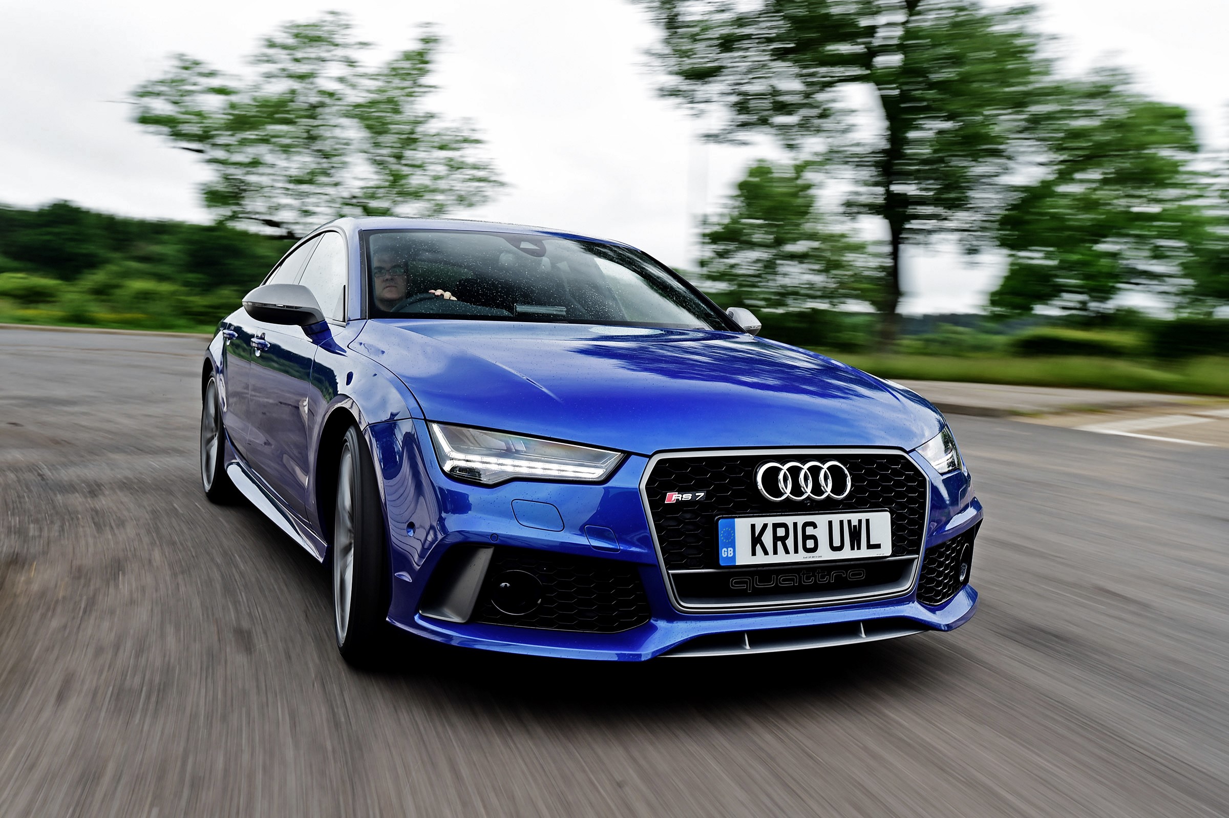 Blue Audi RS 7 driving on a road HD Wallpaper