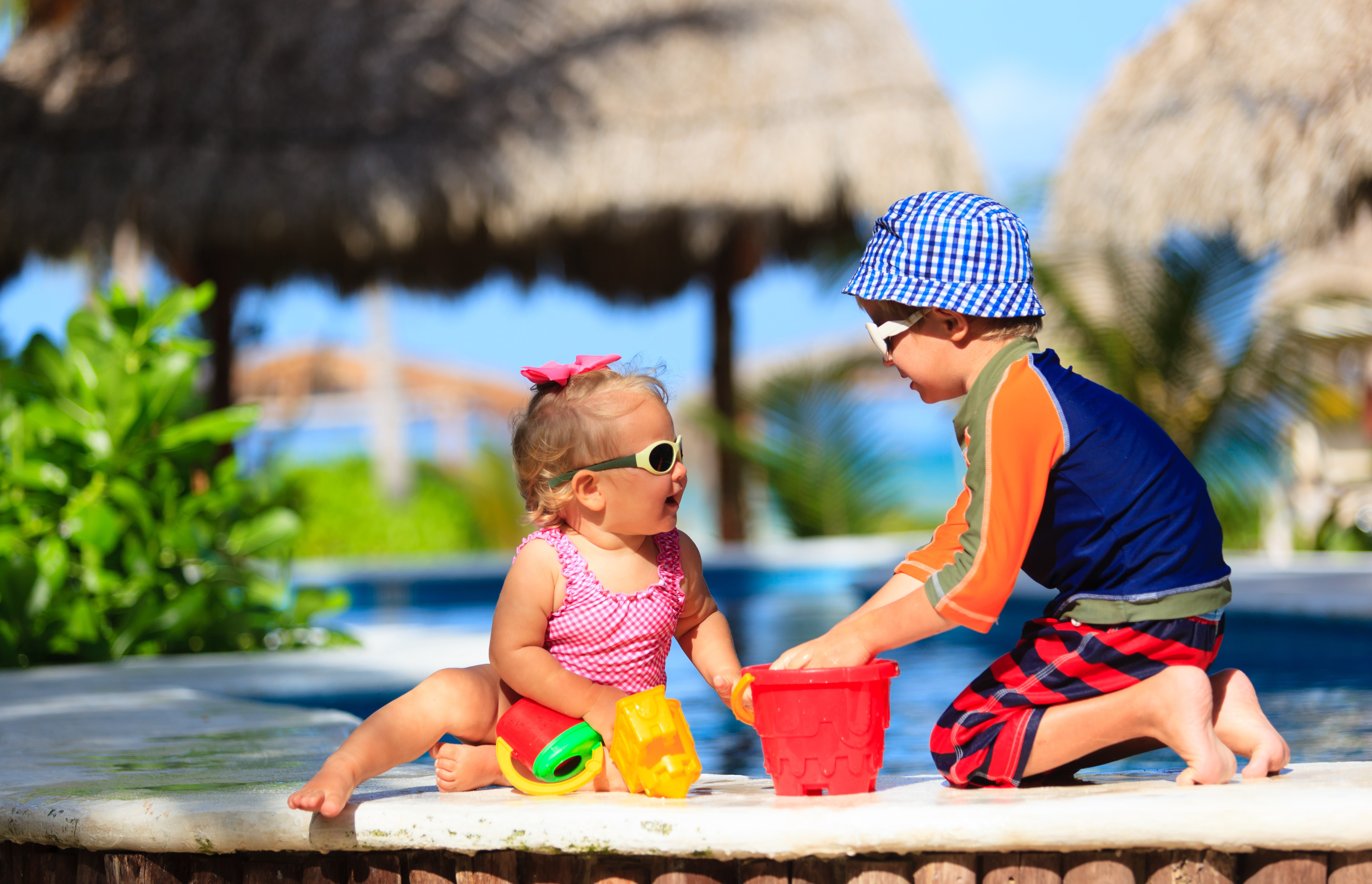 Two children playing with toys by a pool HD Wallpaper