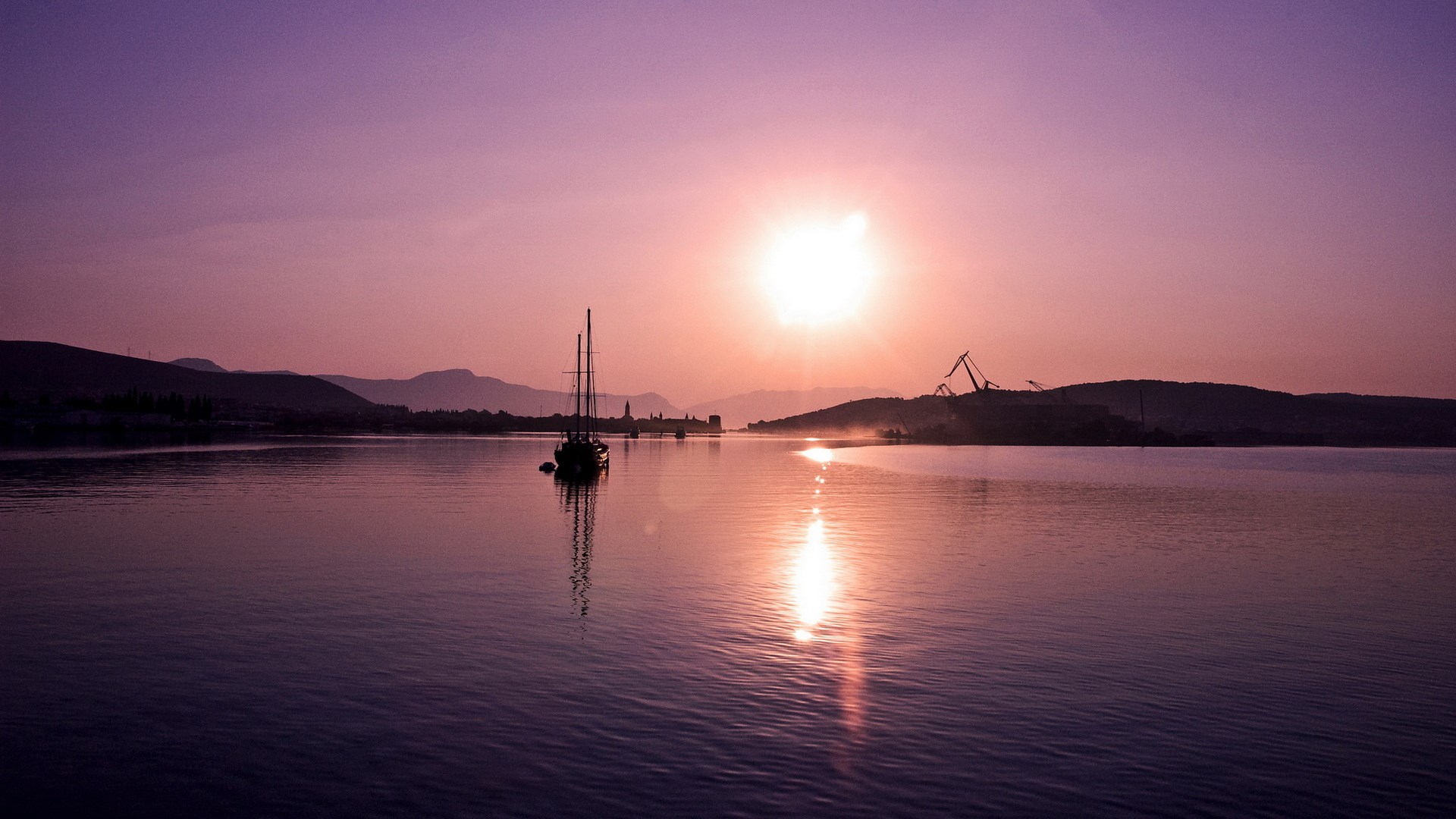 Sailboat on a calm sea at sunset with mountains HD Wallpaper