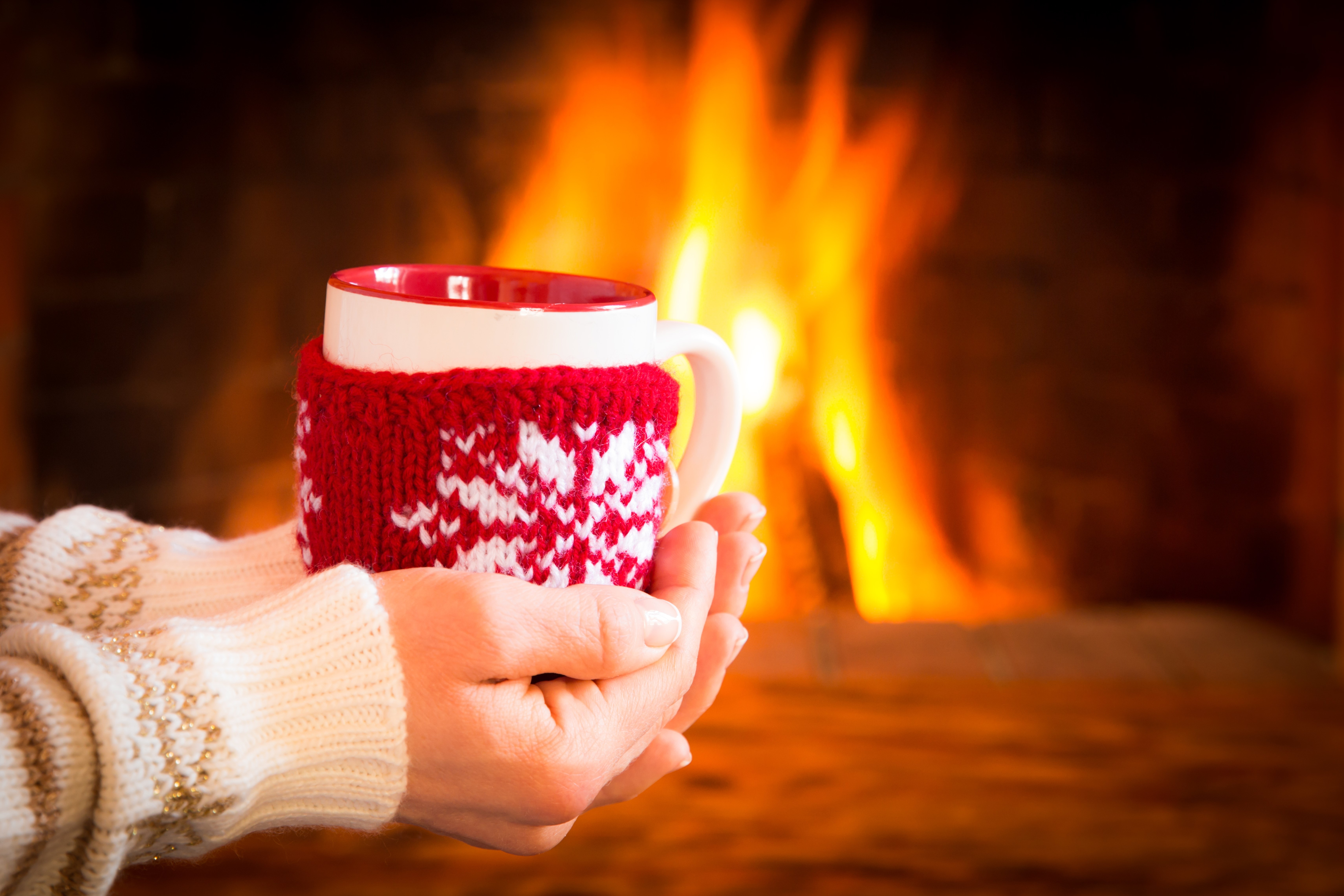 Hands holding a mug by a fireplace HD Wallpaper