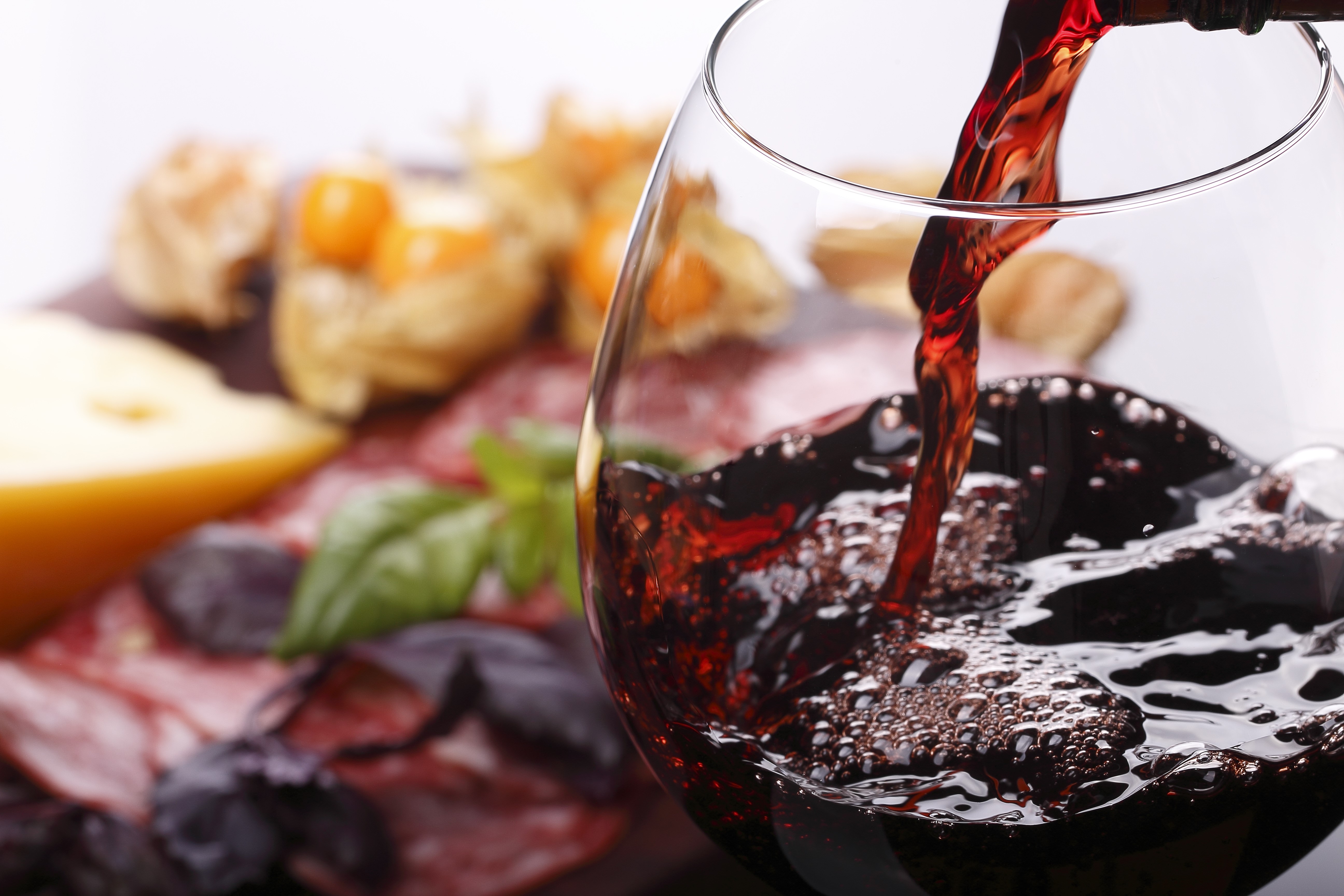 Red wine being poured into a glass with charcuterie HD Wallpaper