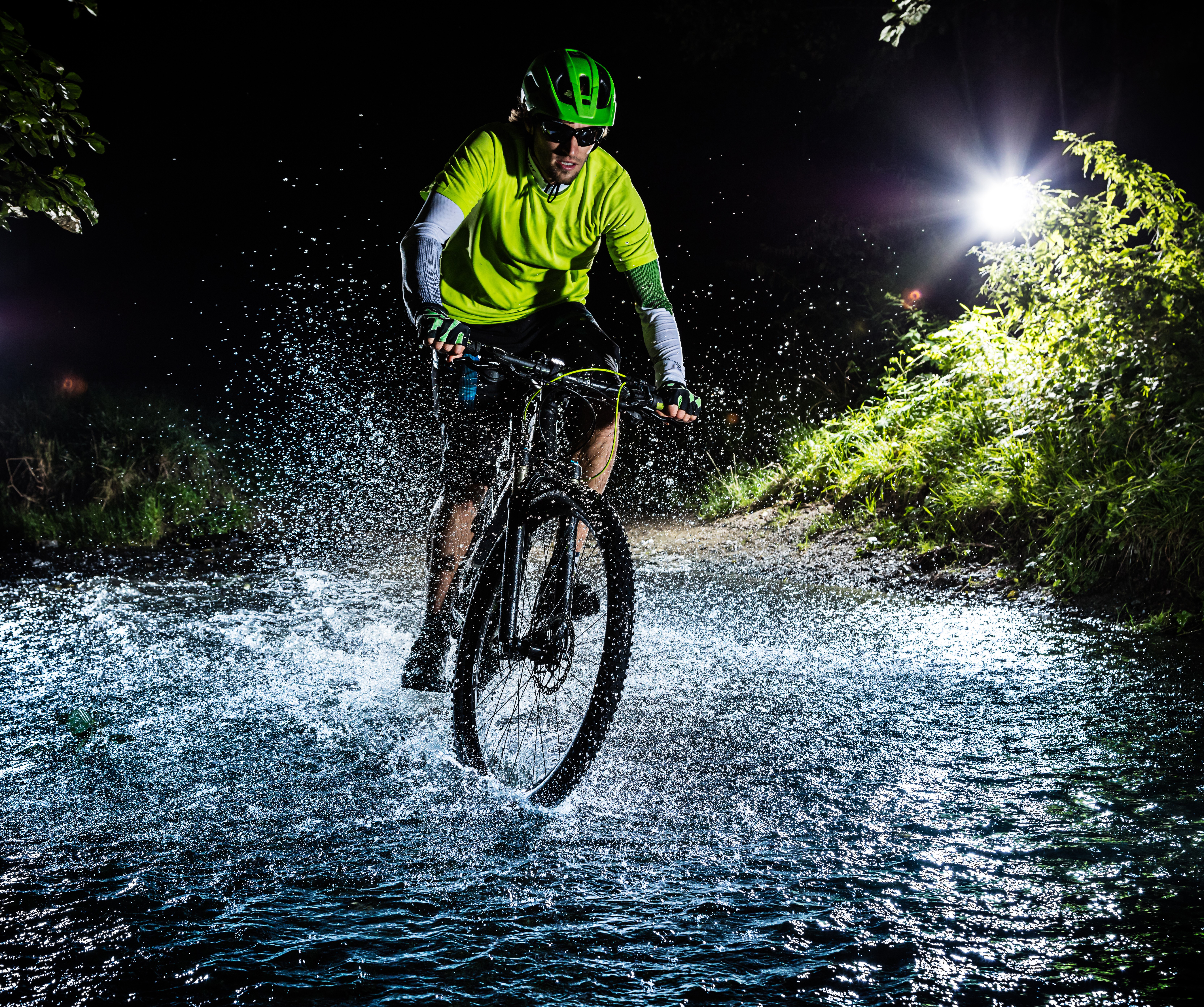 Man riding a bicycle through water at night HD Wallpaper
