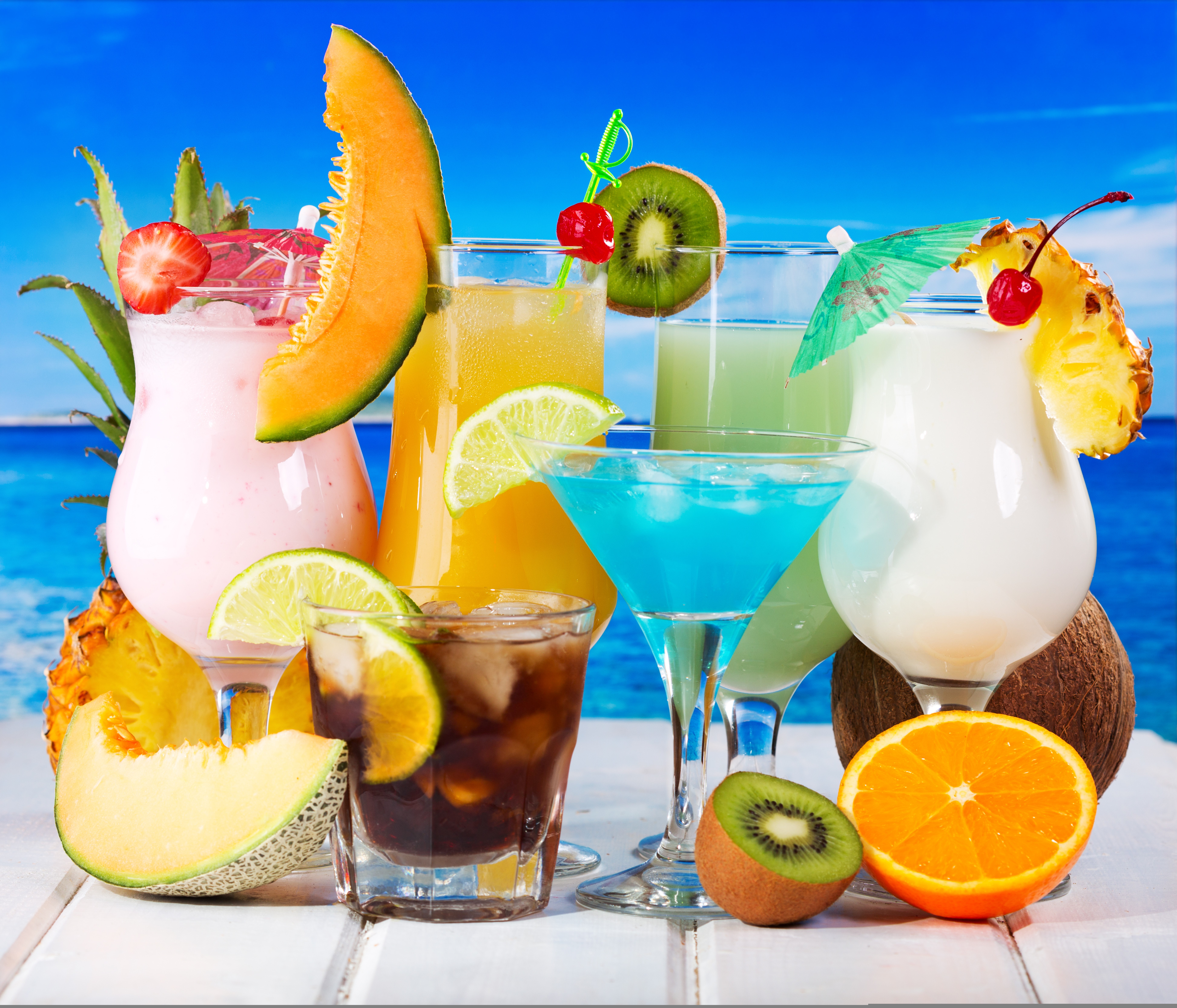 Assorted tropical cocktails with fruits on a beach background HD Wallpaper
