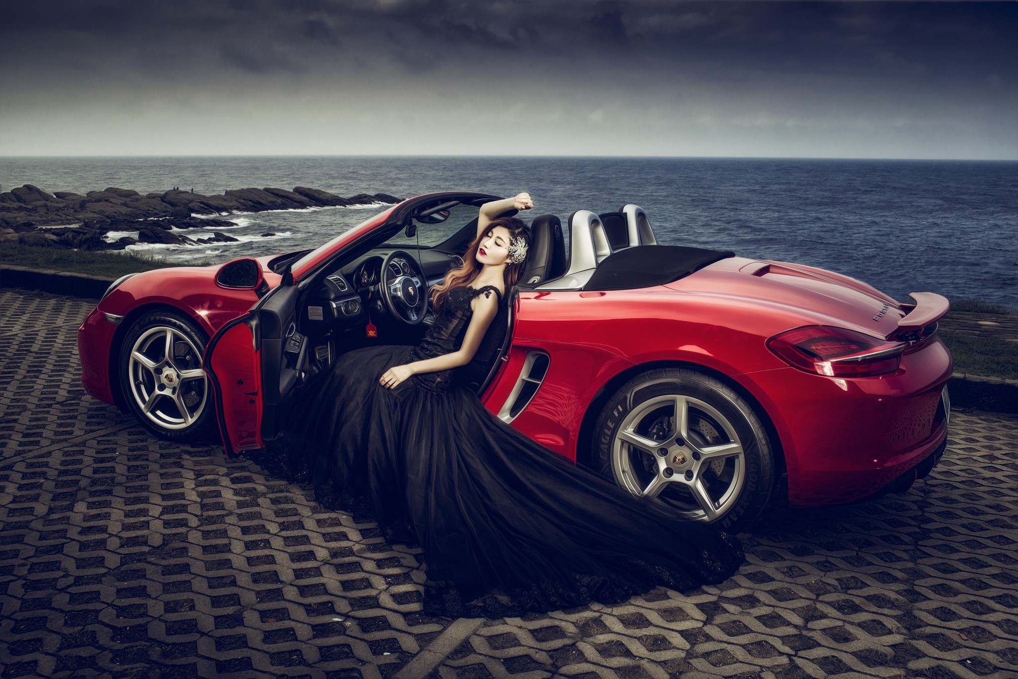 Woman in black dress in red Porsche convertible by the sea HD Wallpaper