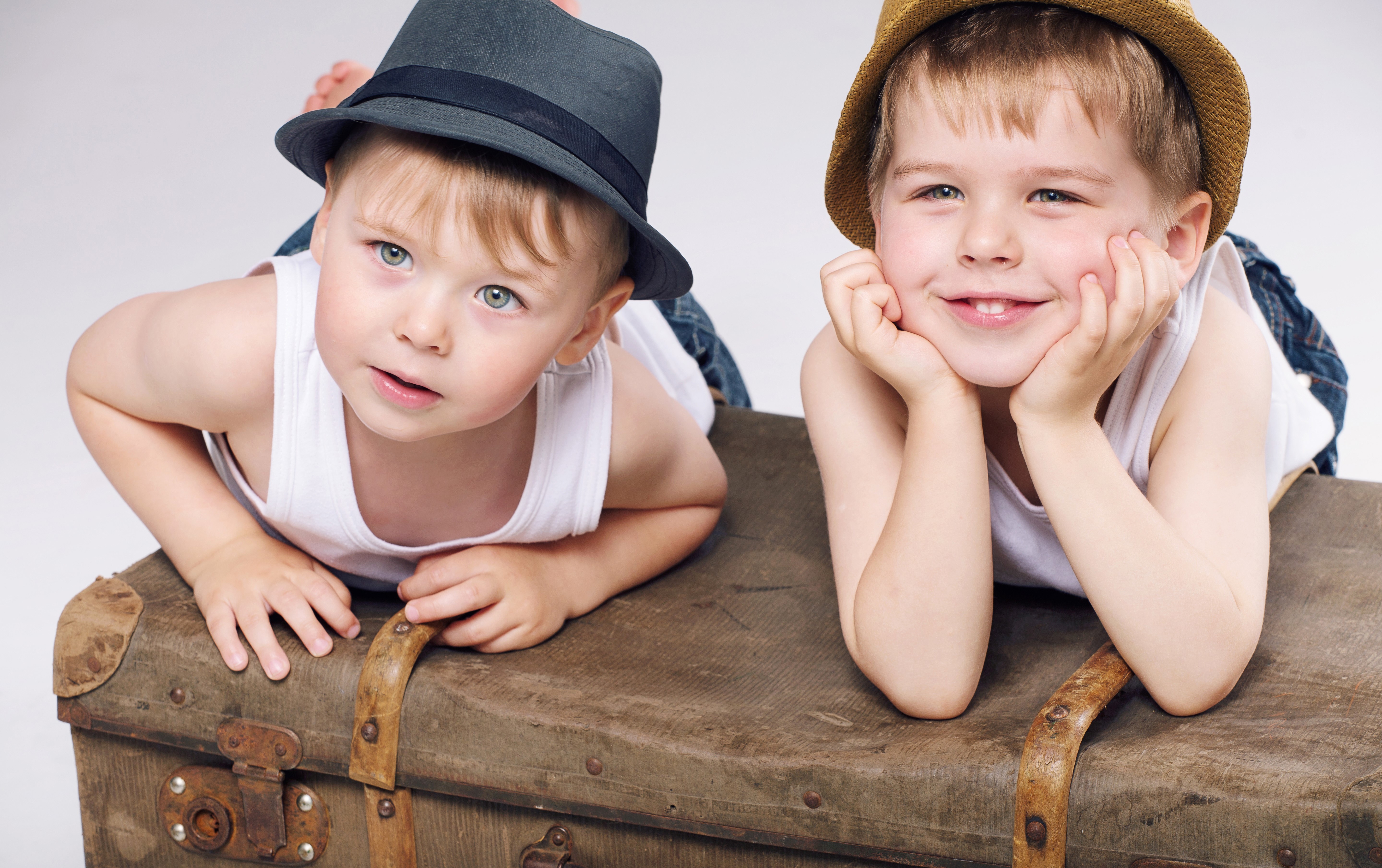 Two boys wearing hats on a suitcase HD Wallpaper