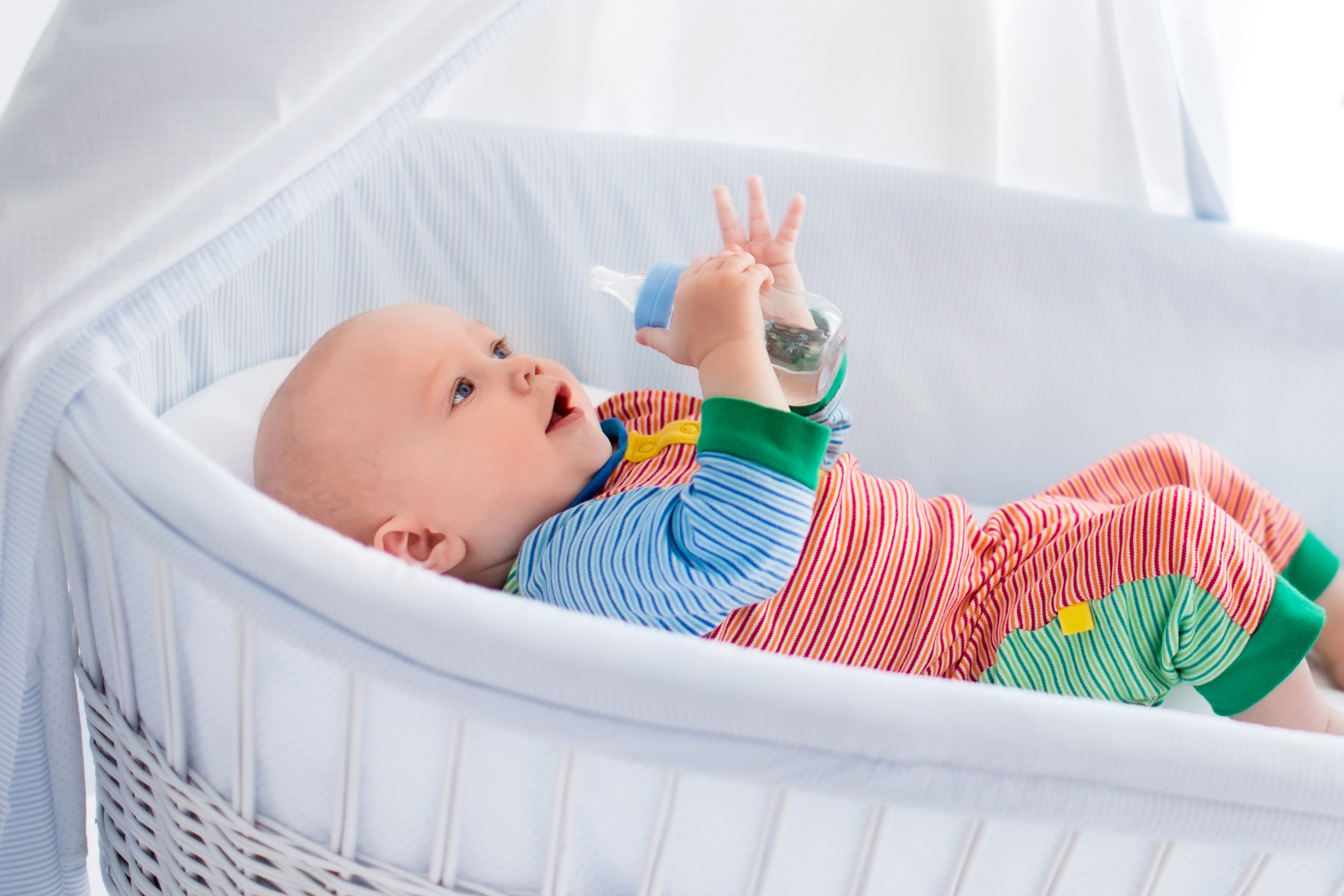 Baby holding a bottle in a crib HD Wallpaper