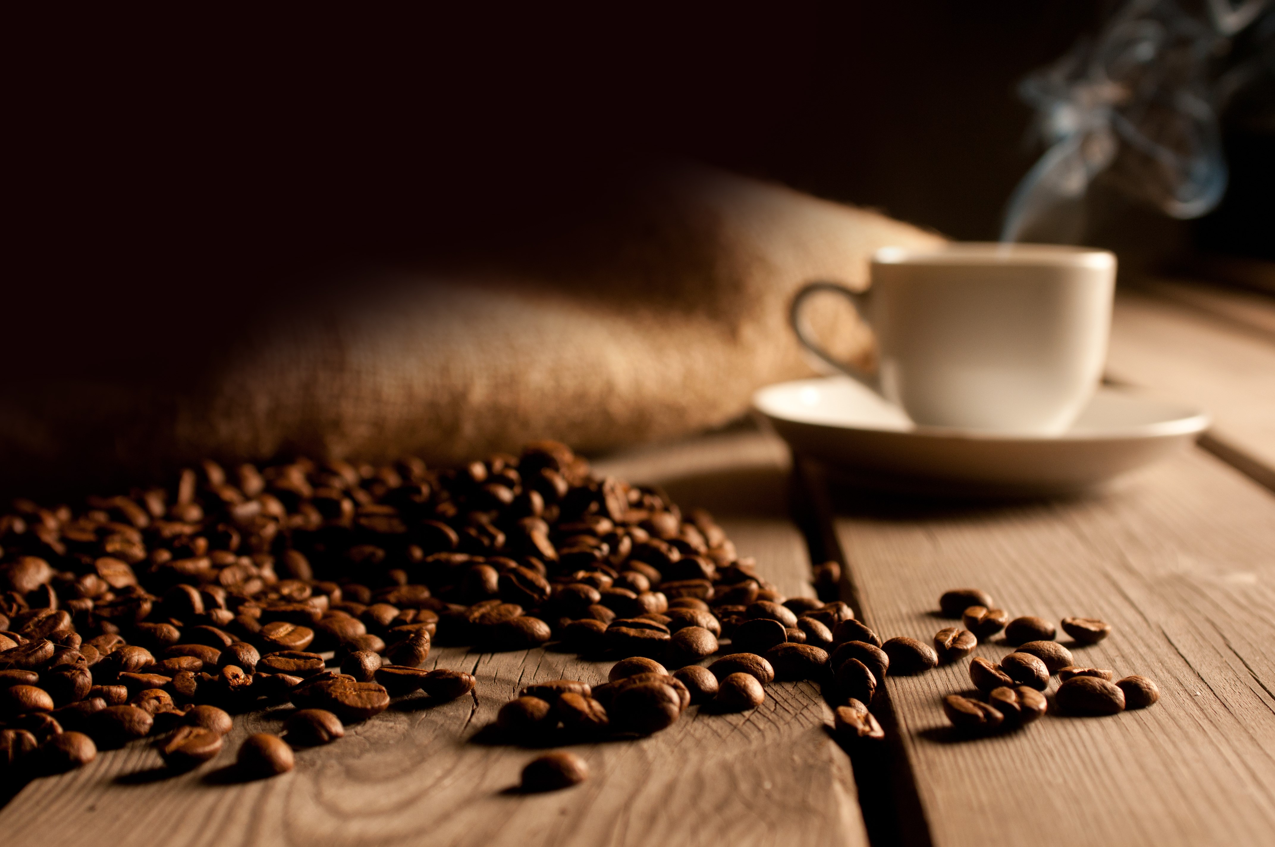 Coffee beans, cup, saucer, and burlap sack on wood HD Wallpaper