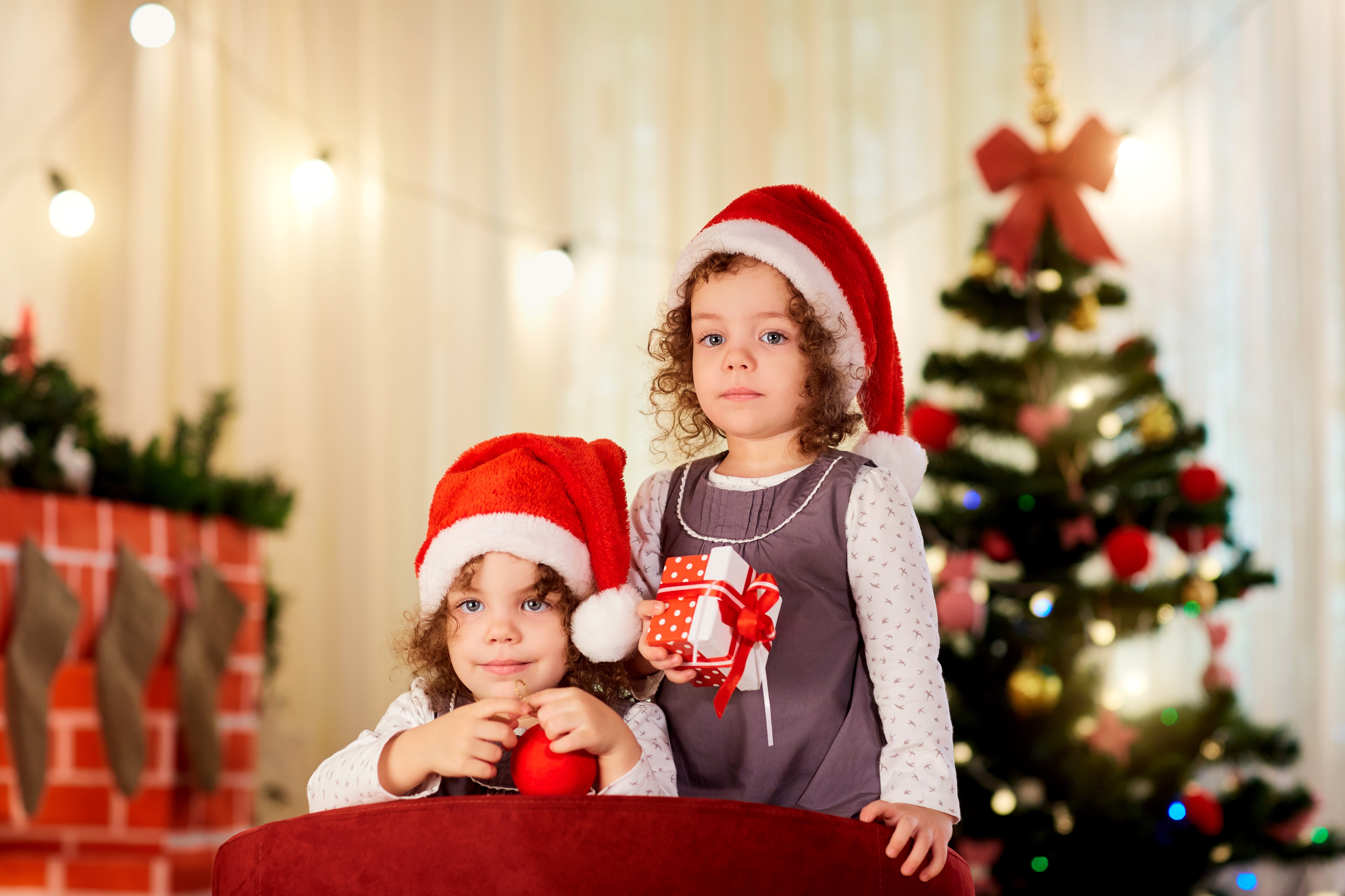 Two little girls in Santa hats with Christmas gifts HD Wallpaper