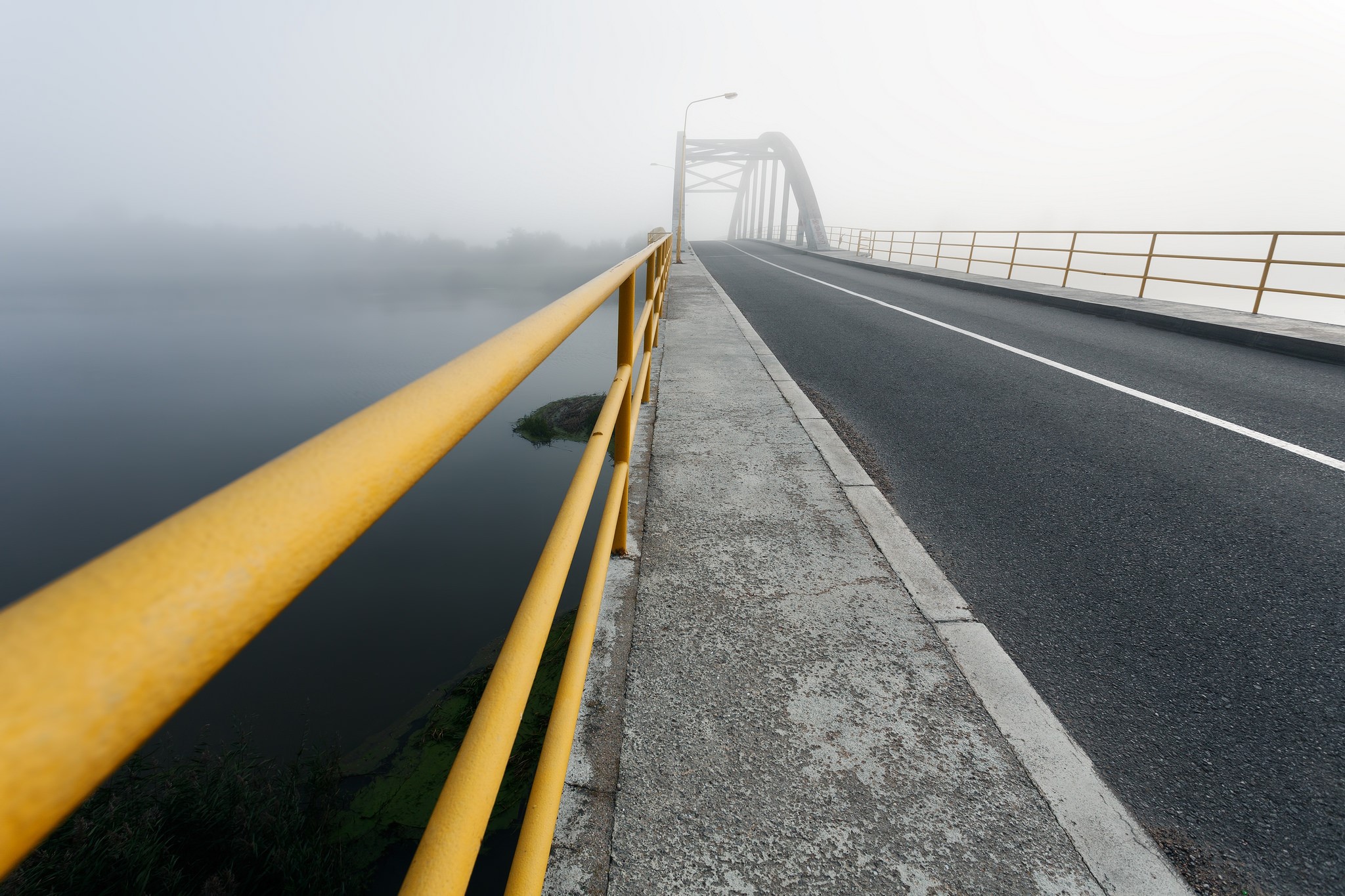Bridge over water in fog with yellow railing HD Wallpaper