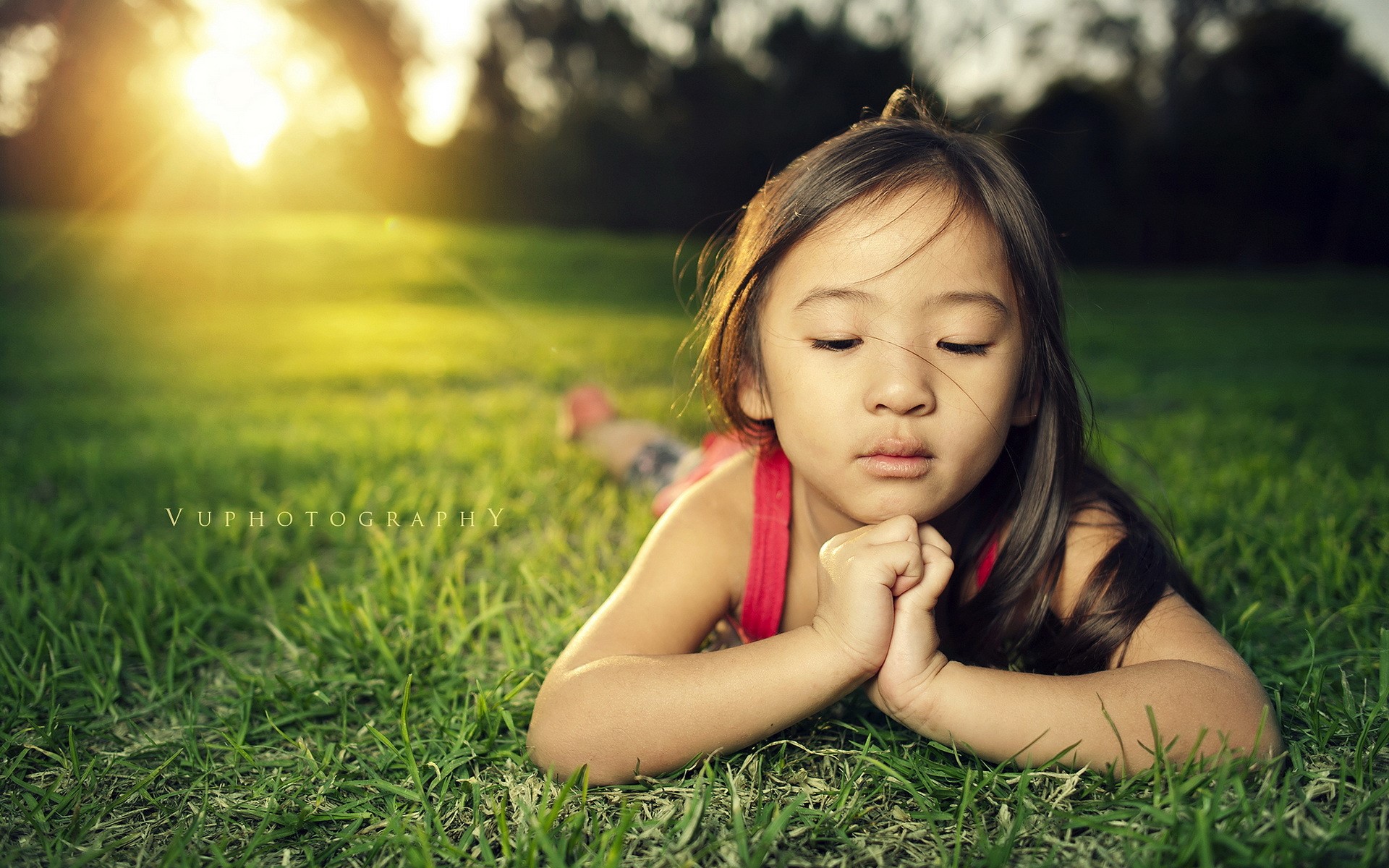Young Girl Lying on Green Grass at Sunset HD Wallpaper