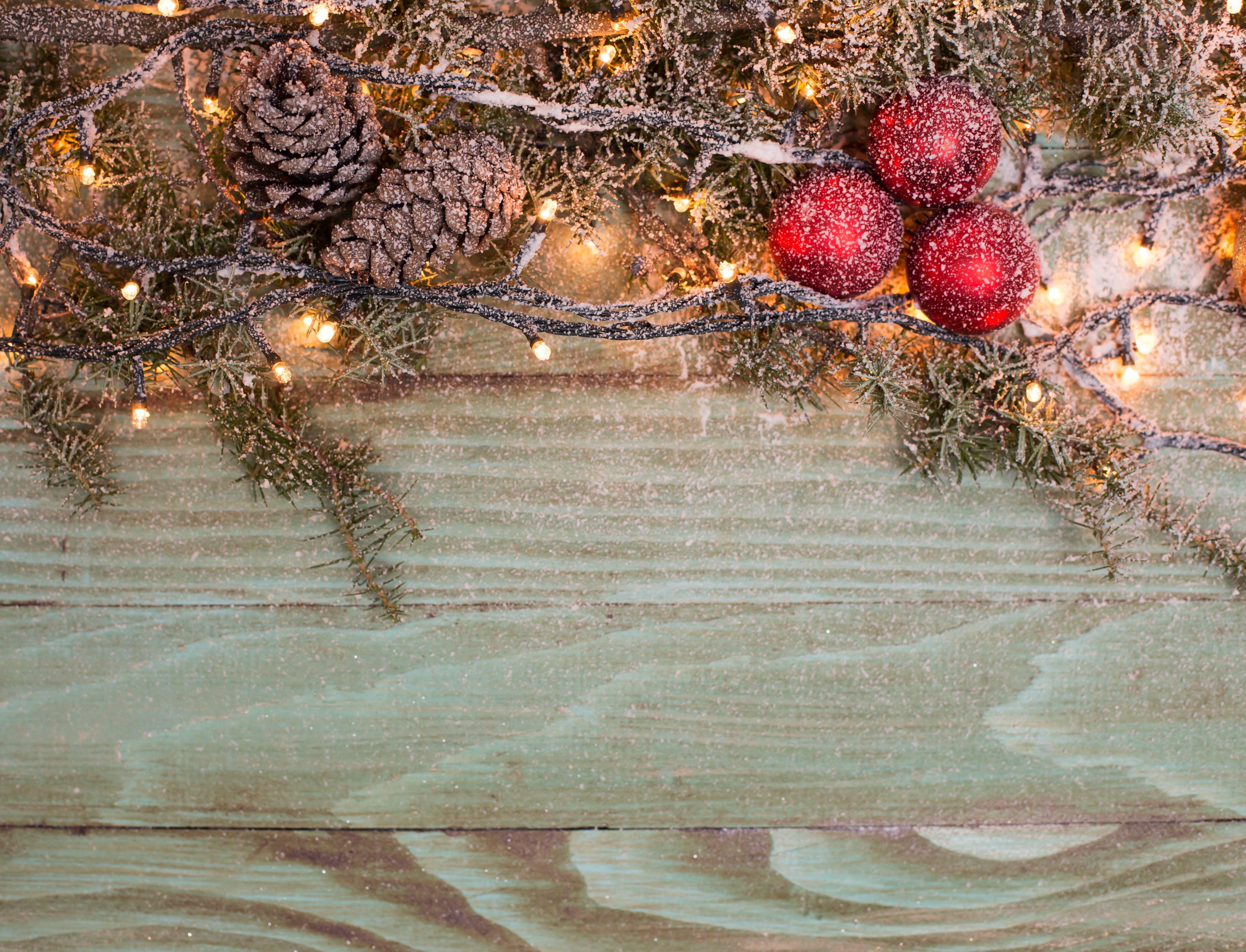 Christmas branches with pine cones, ornaments, and fairy lights on wood HD Wallpaper