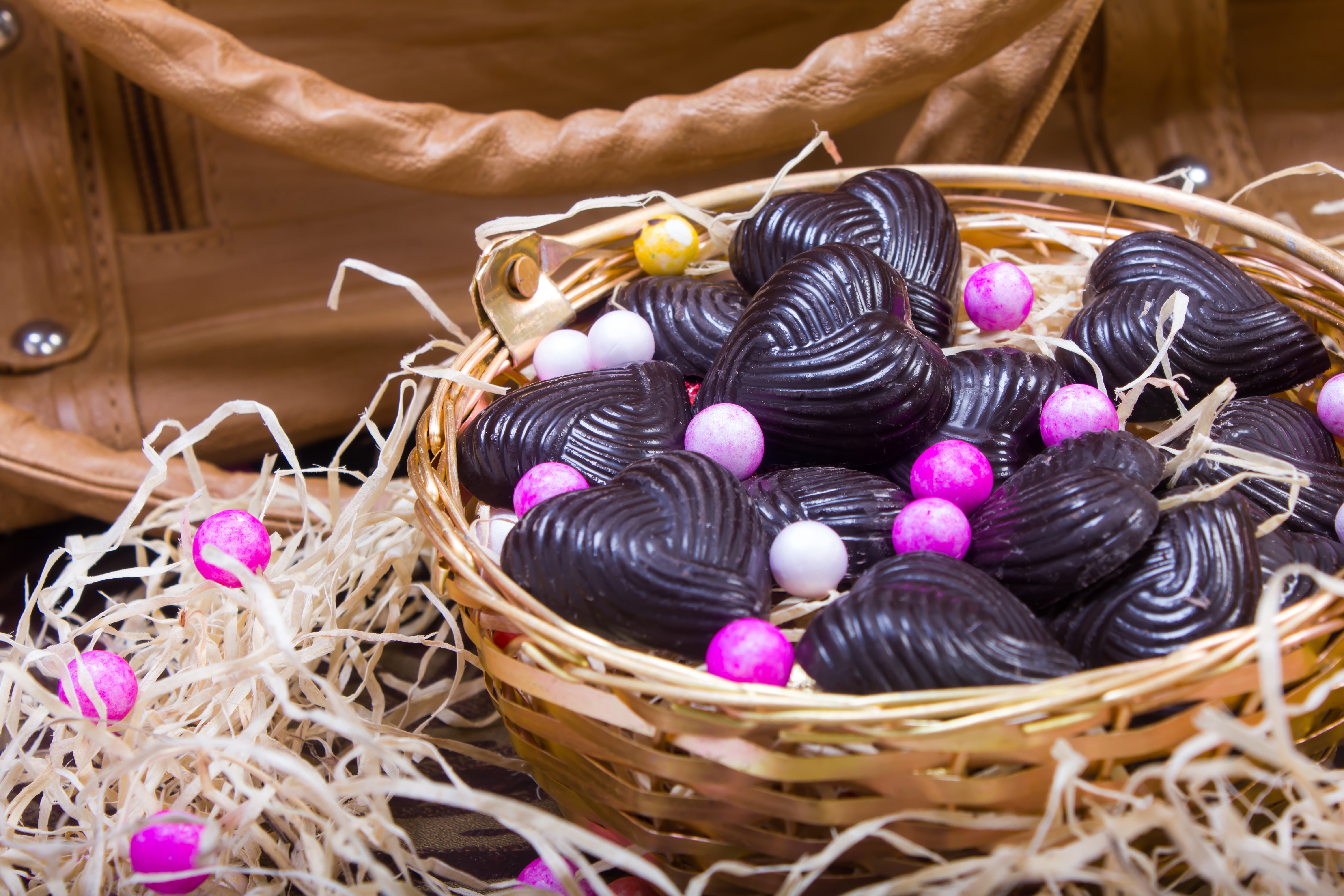 Heart-shaped chocolates and candies in a wicker basket HD Wallpaper